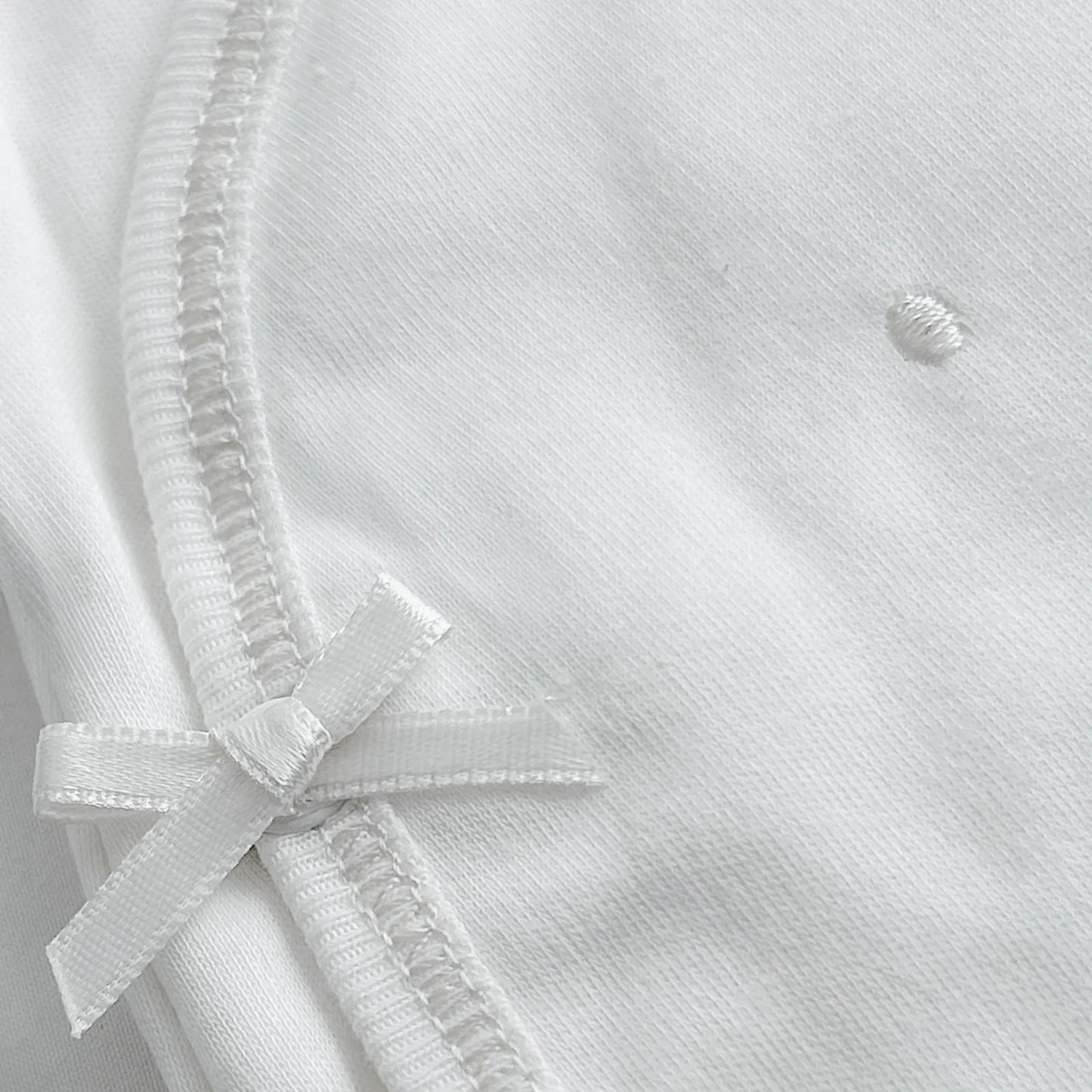 Detalle de body cruzado con pantalones com pies con bordado de lunares blanco