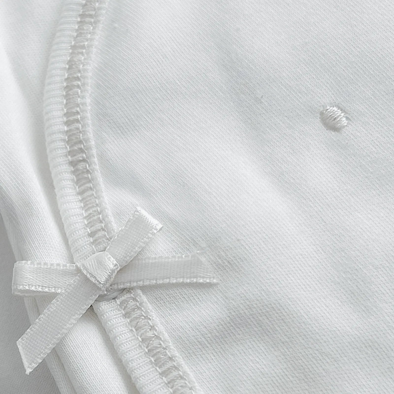 Detalle de body cruzado con pantalones com pies con bordado de lunares blanco