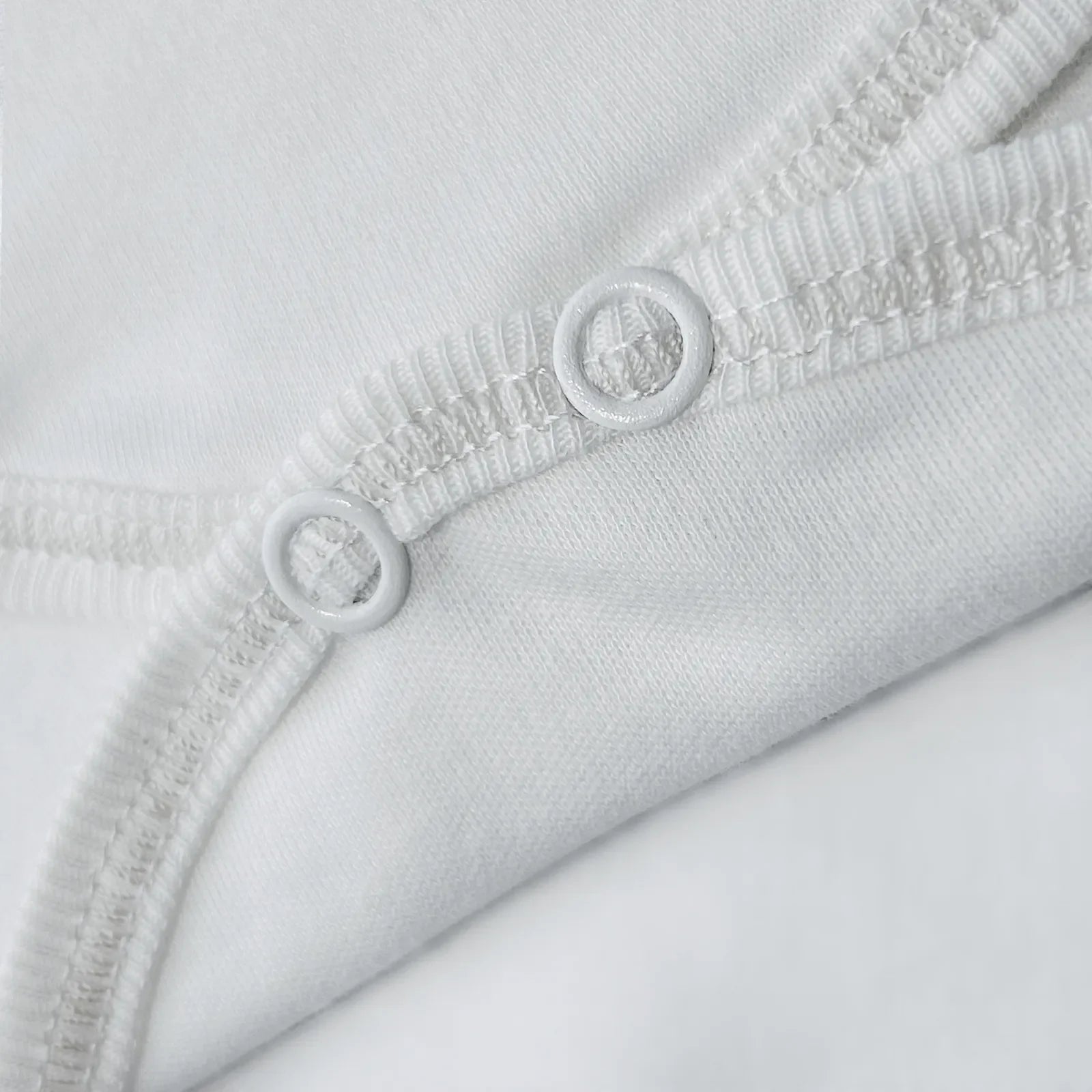 Detalle de body cruzado con pantalones com pies con bordado de lunares blanco