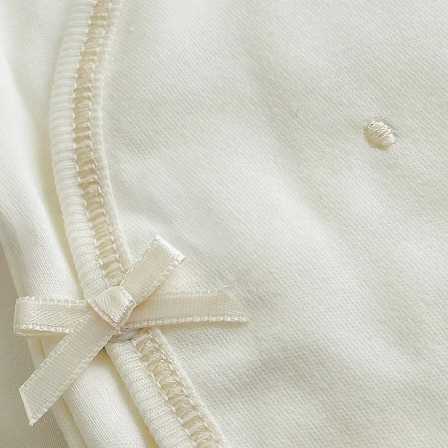 Detalle de body cruzado con pantalones com pies perla con bordado de lunares