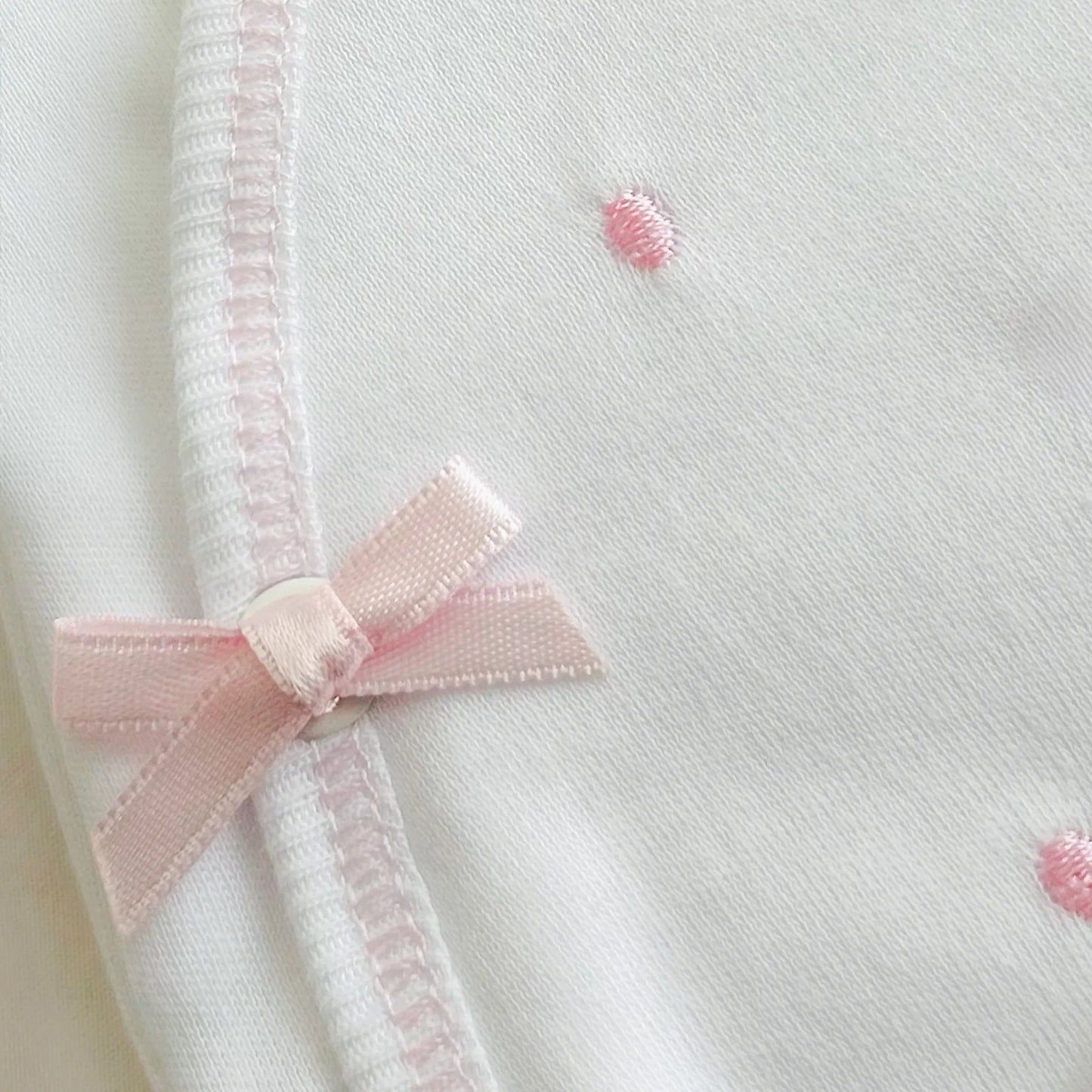 Detalle de body cruzado con pantalones com pies con bordado de lunares rosa