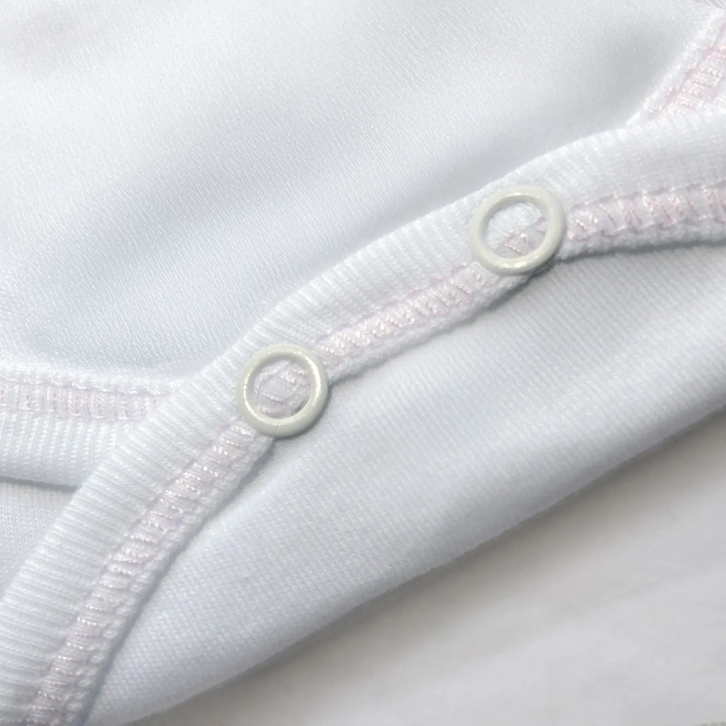 Detalle de body cruzado con pantalones com pies con bordado de lunares rosa