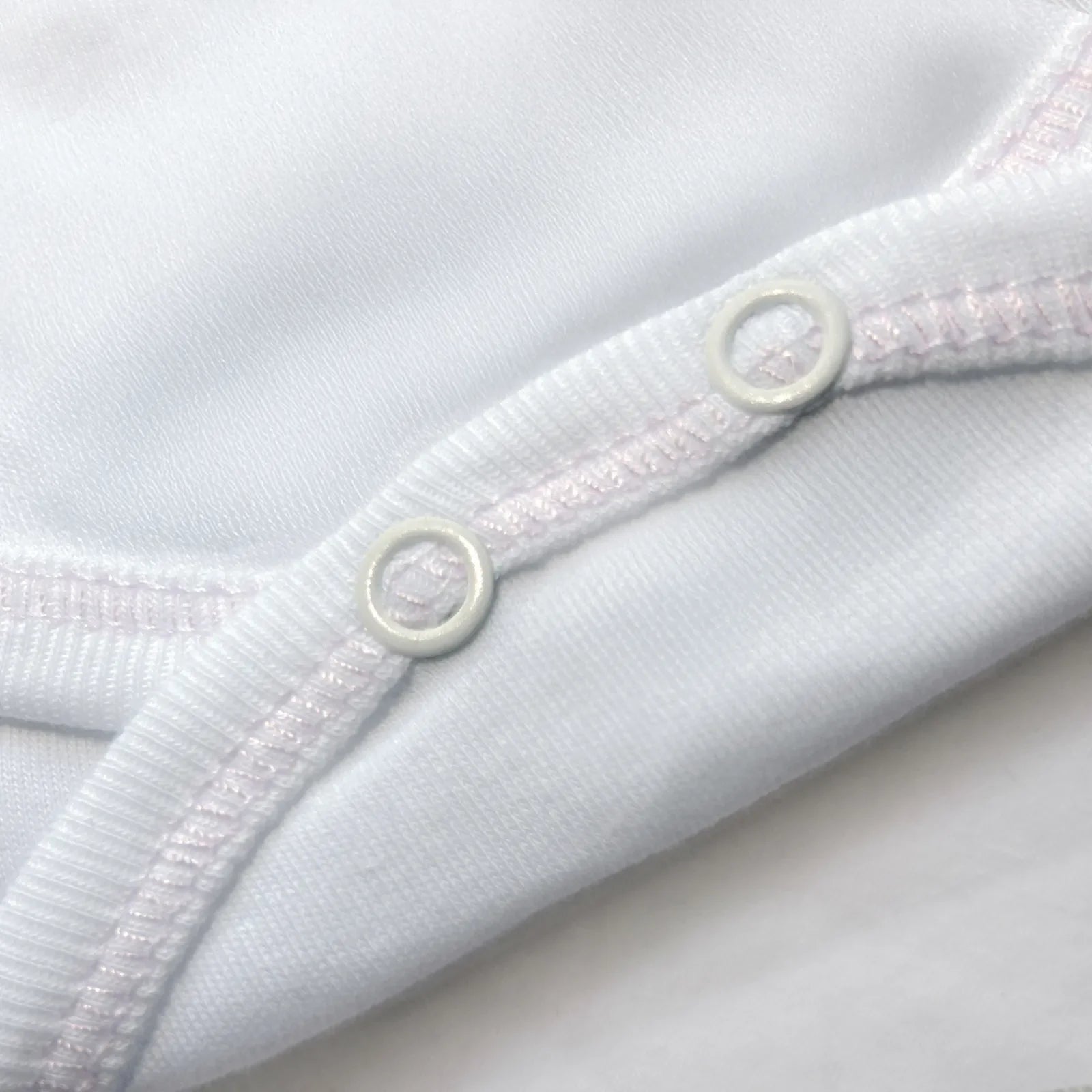 Detalle de body cruzado con pantalones com pies con bordado de lunares rosa