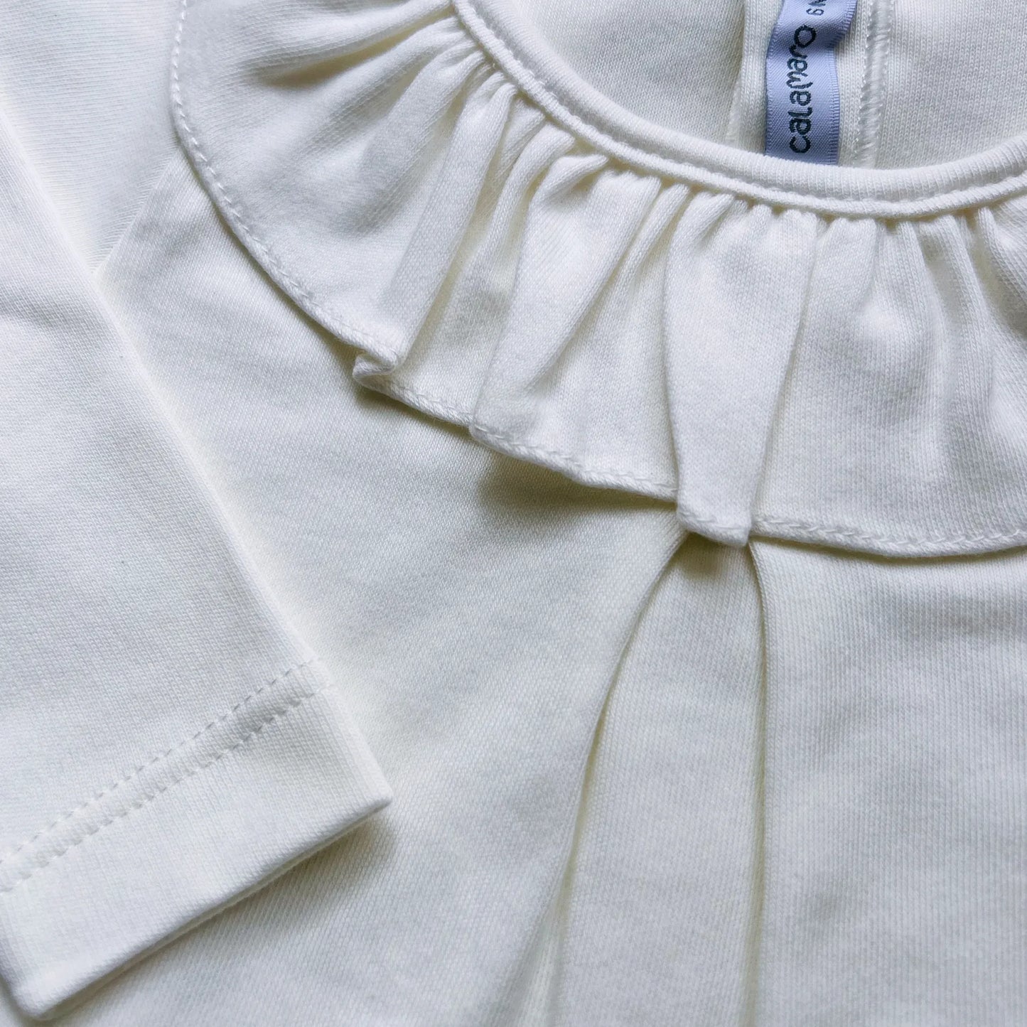 Detalle de camisa de niña con volante en el cuello y pliegue delantero perla