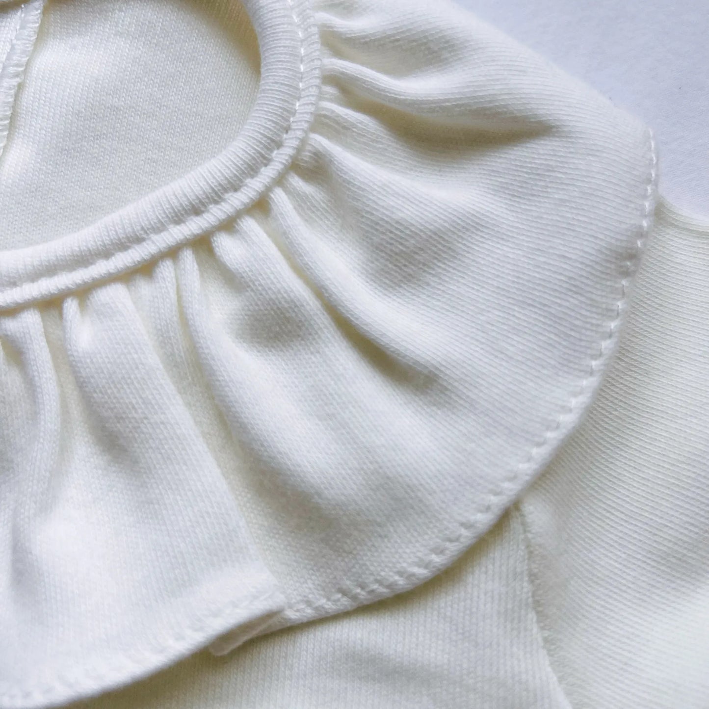 Detalle de camisa de niña con volante en el cuello y pliegue delantero perla