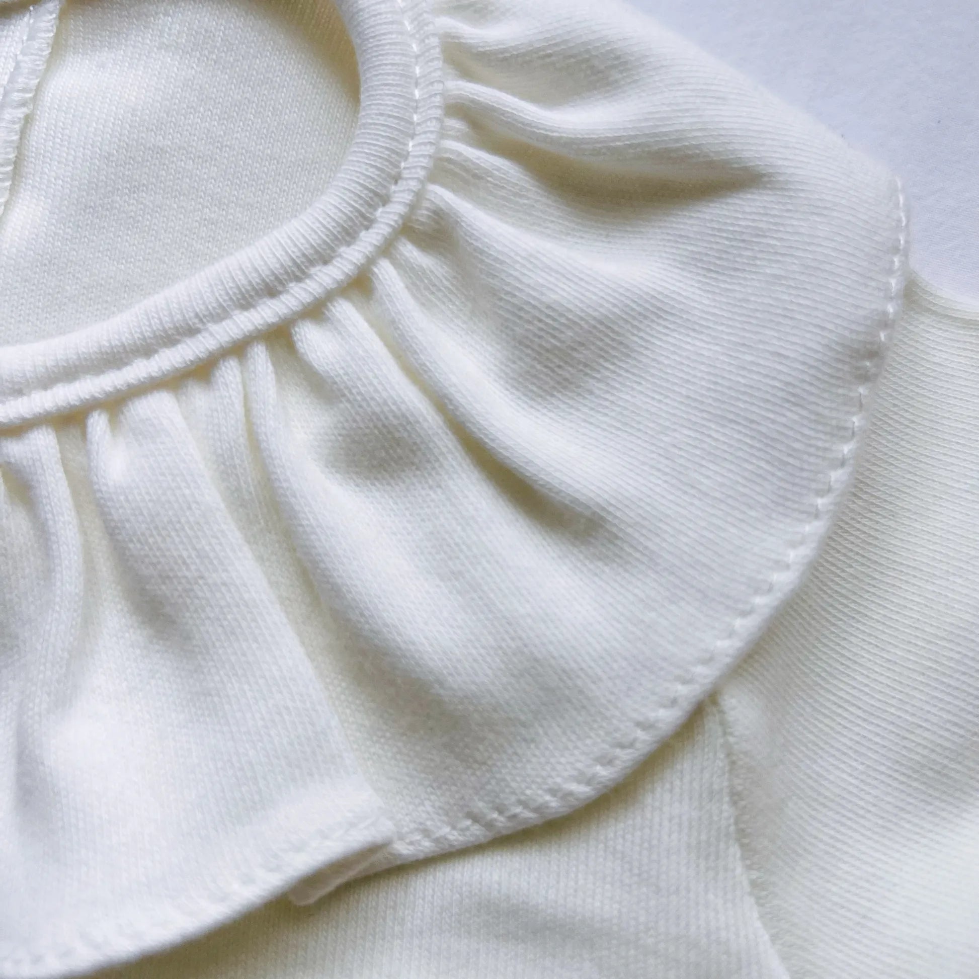 Detalle de camisa de niña con volante en el cuello y pliegue delantero perla