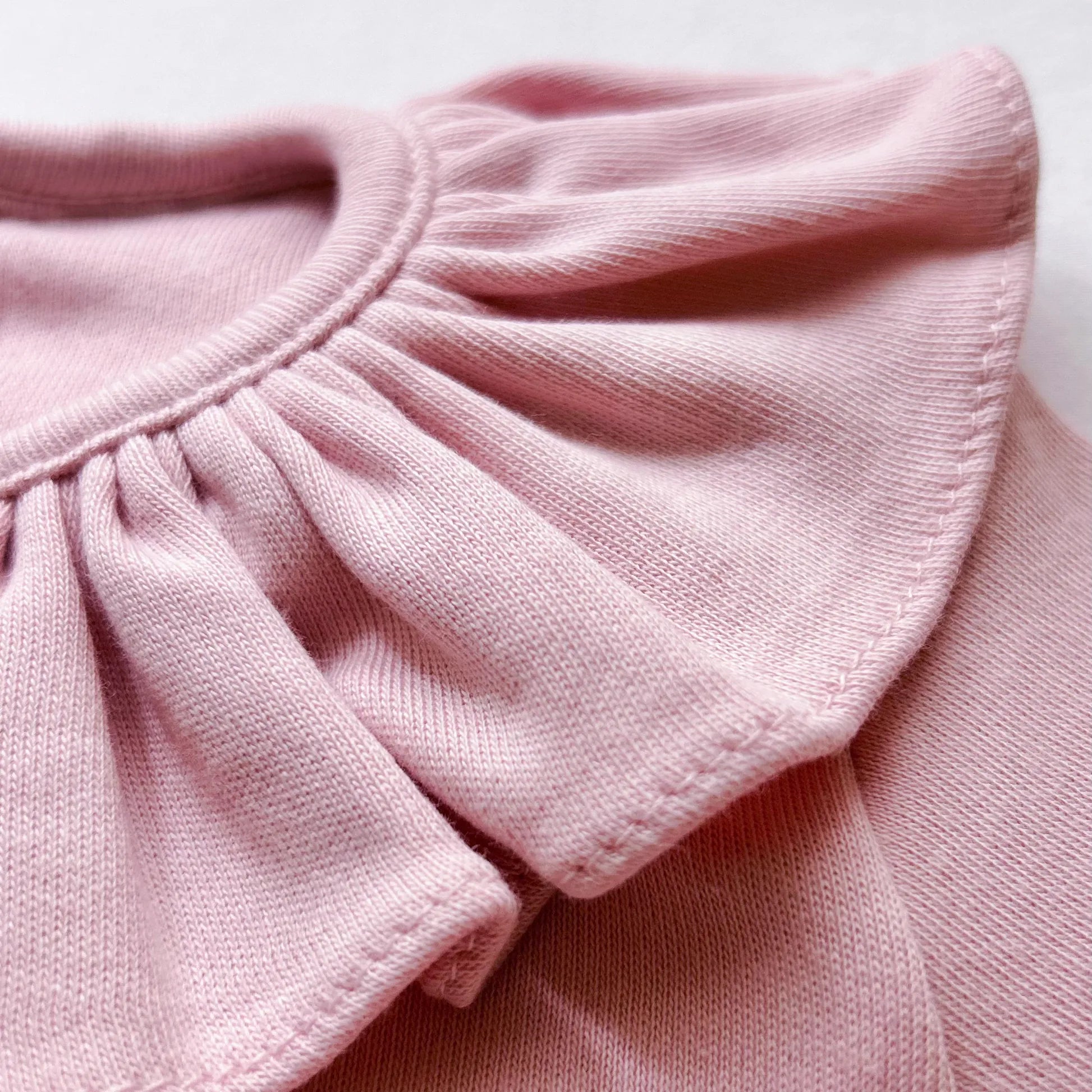 Detalle de camisa de niña con volante en el cuello y pliegue delantero rosa