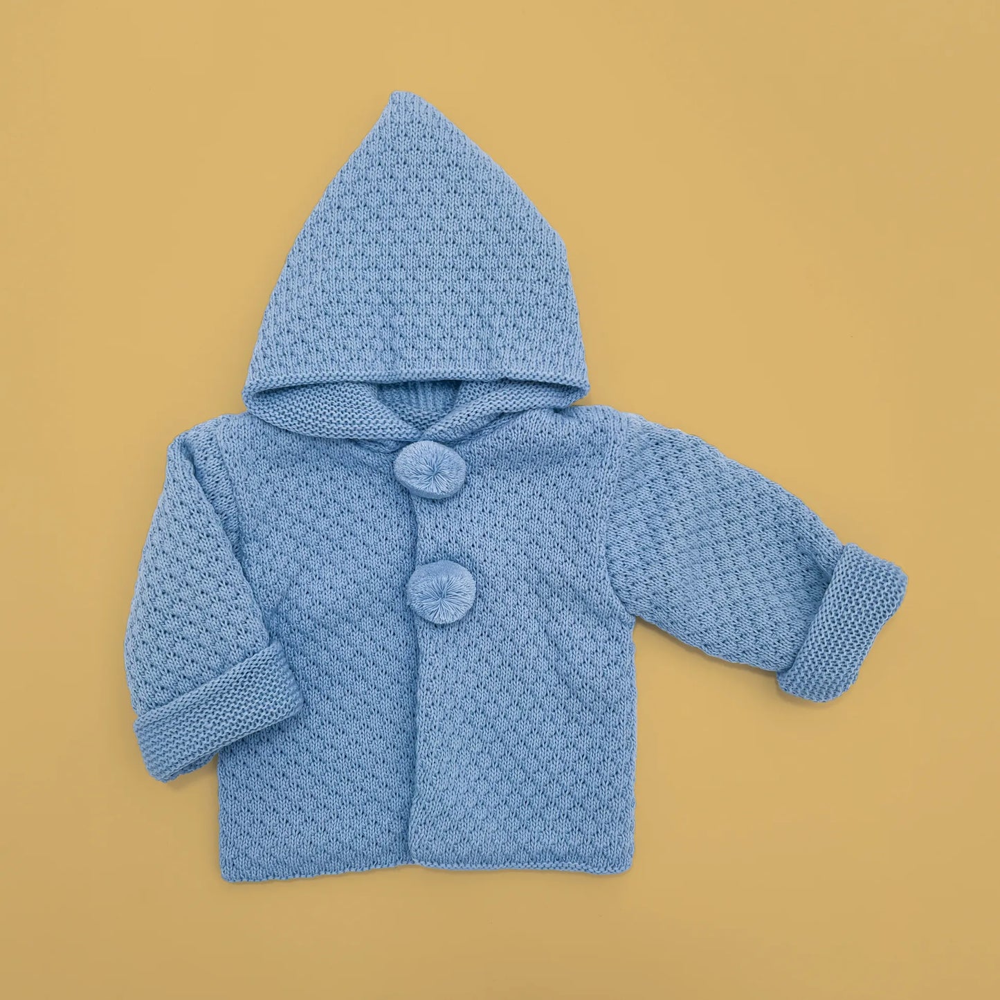 Chaqueta de punto con capucha y pompones en la zona de los botones azul
