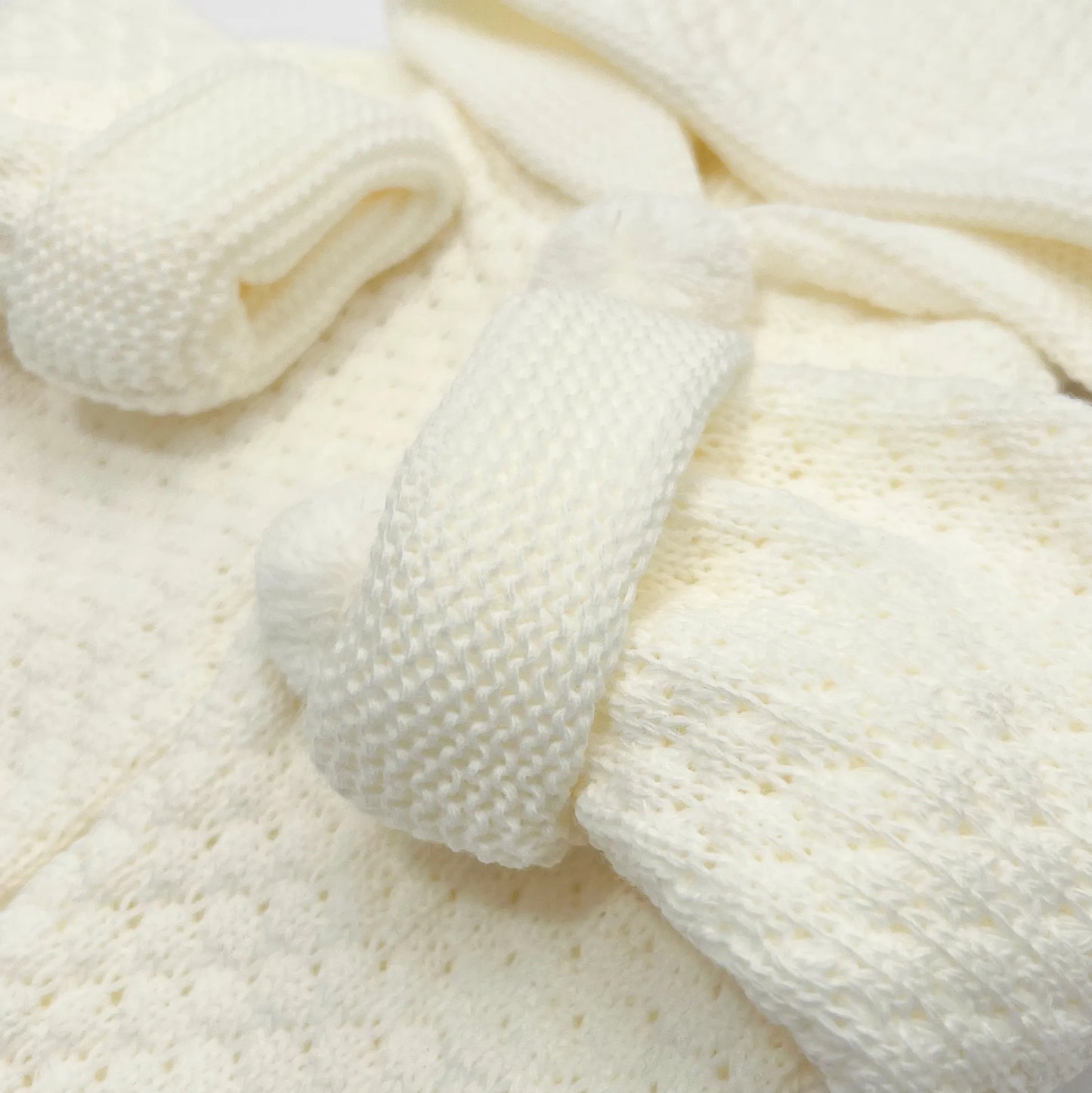 Detalle de chaqueta de punto con capucha y pompones en la zona de los botones perla