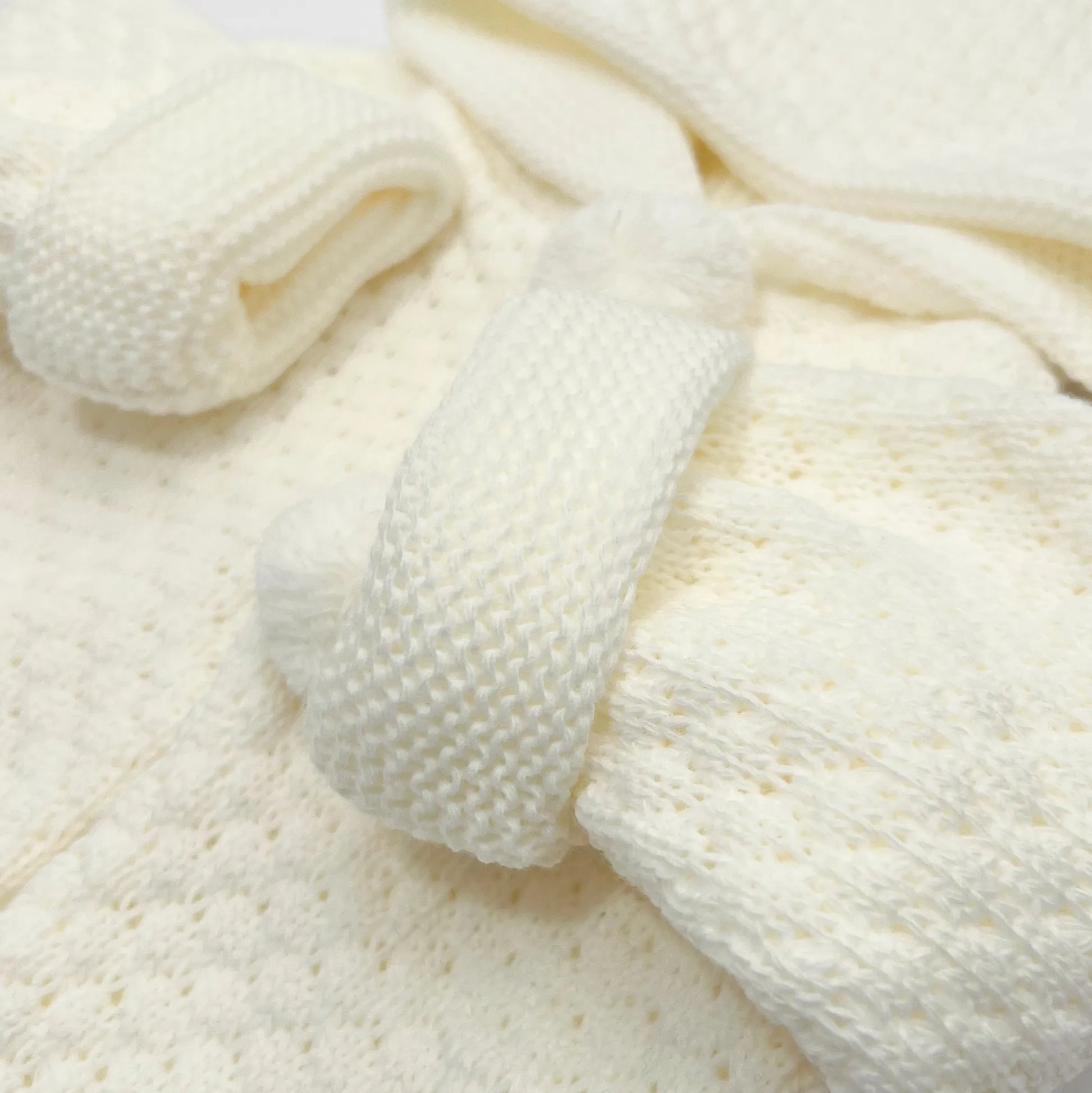 Detalle de chaqueta de punto con capucha y pompones en la zona de los botones perla