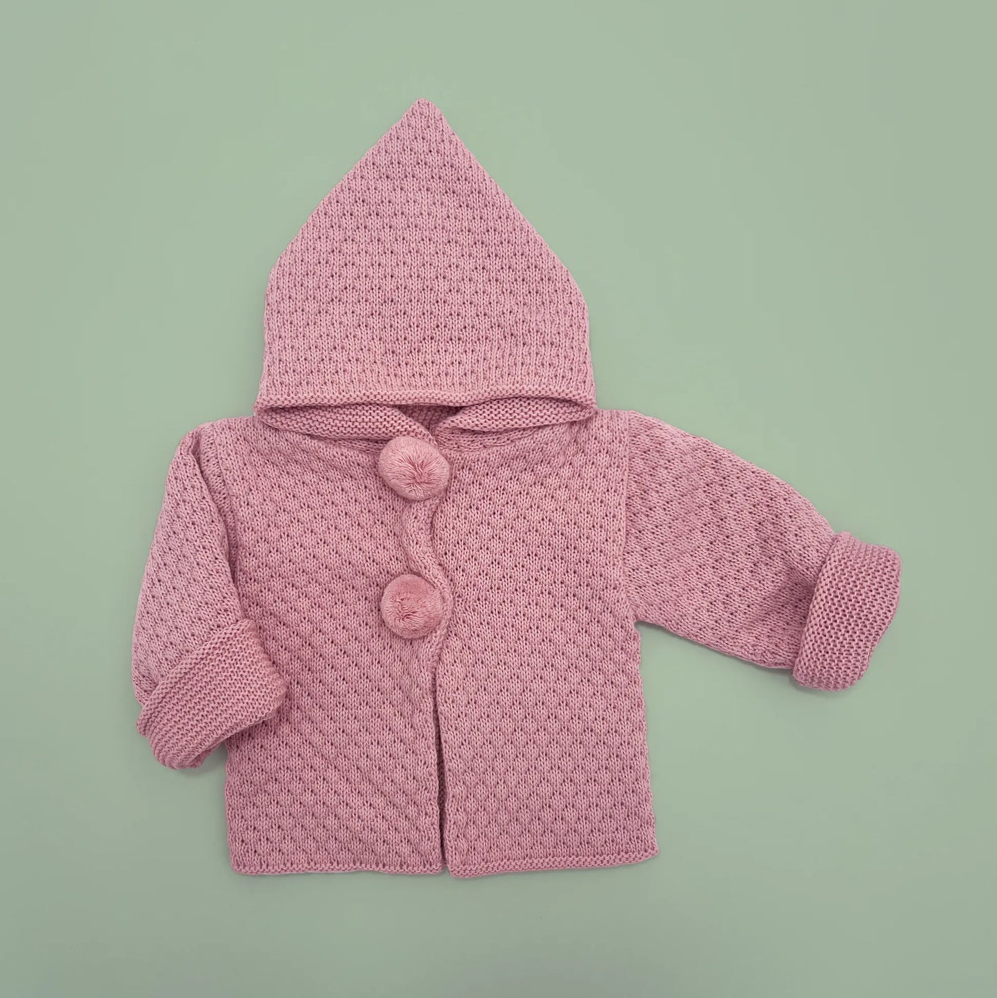 Chaqueta de punto con capucha y pompones en la zona de los botones rosa
