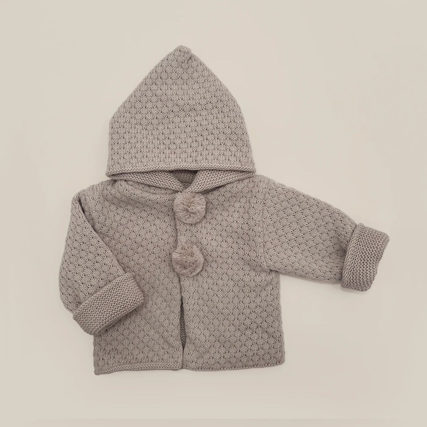 Chaqueta de punto con capucha y pompones en la zona de los botones topo