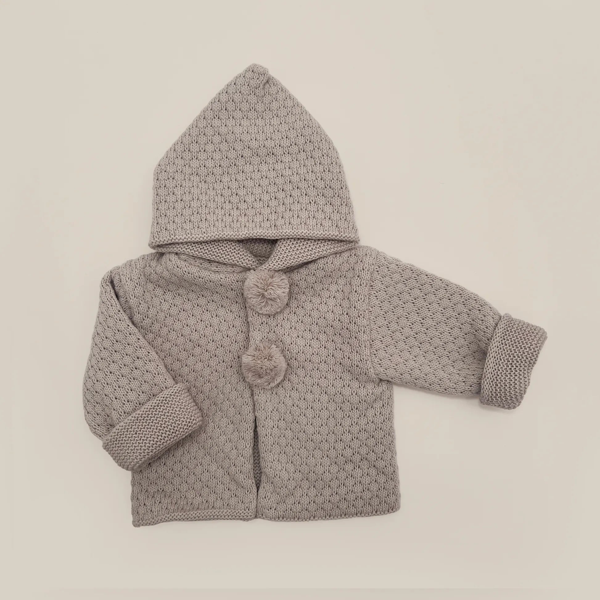 Chaqueta de punto con capucha y pompones en la zona de los botones topo