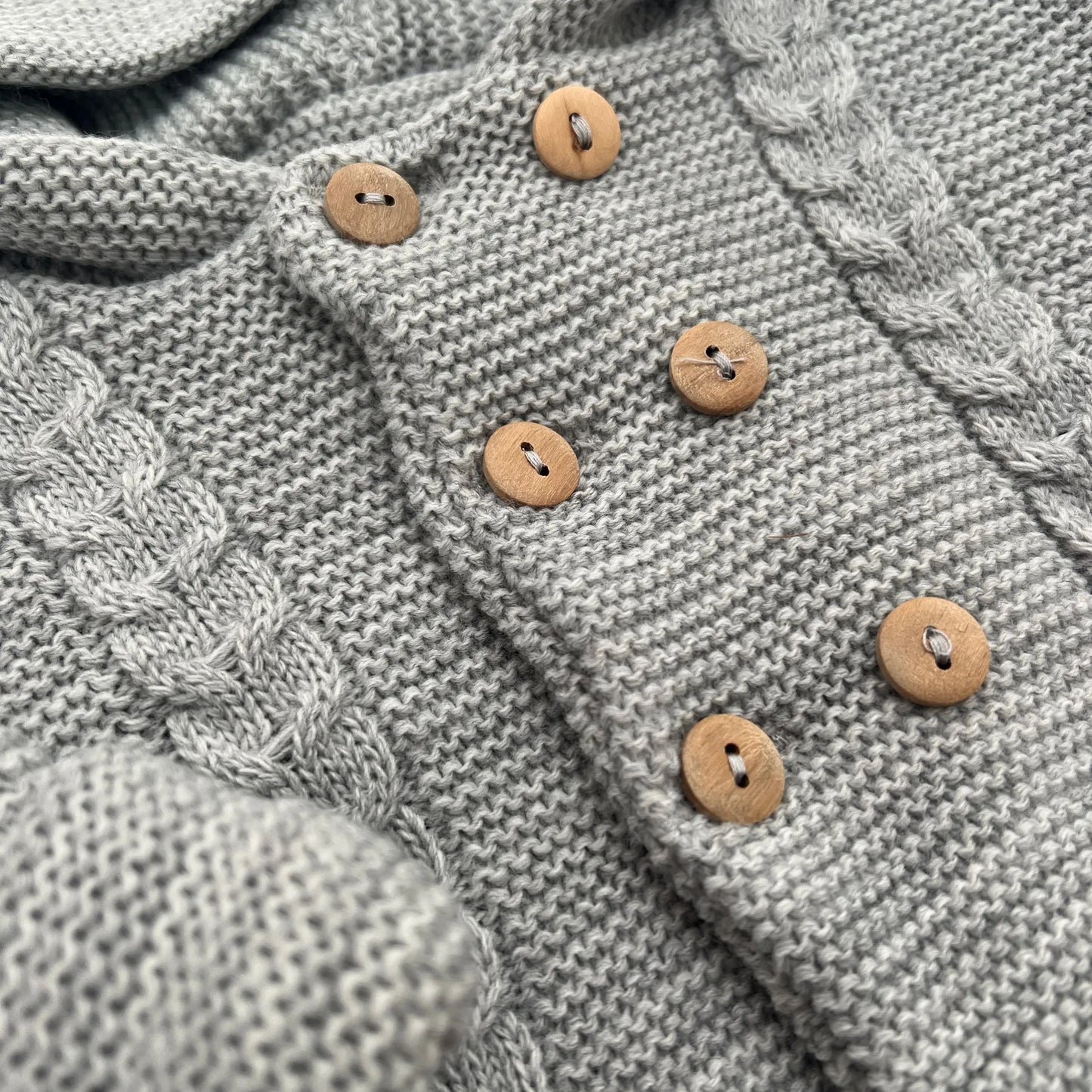 Detalles de chaqueta de punto con capucha y detalles trenzados en la parte delantera gris