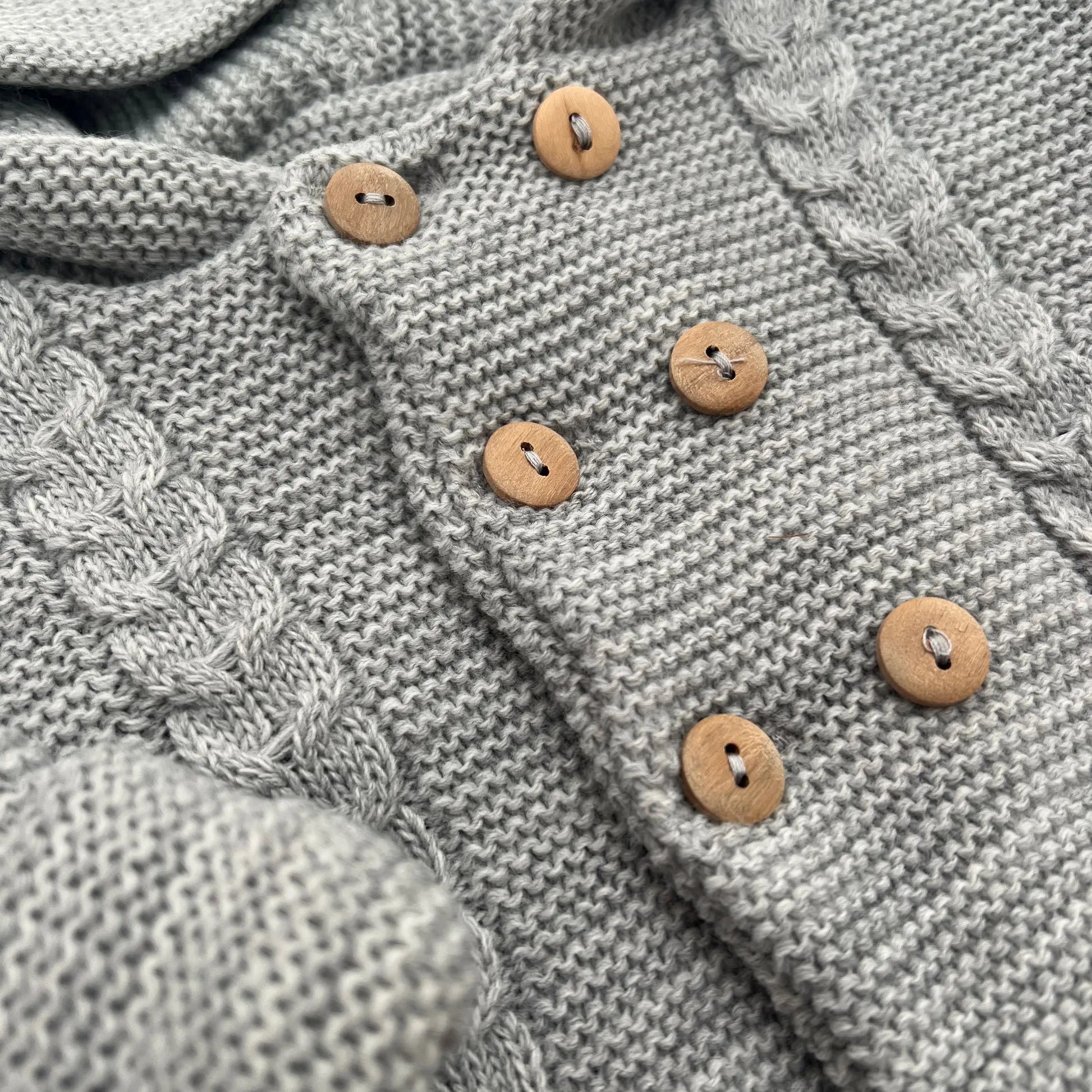 Detalles de chaqueta de punto con capucha y detalles trenzados en la parte delantera gris