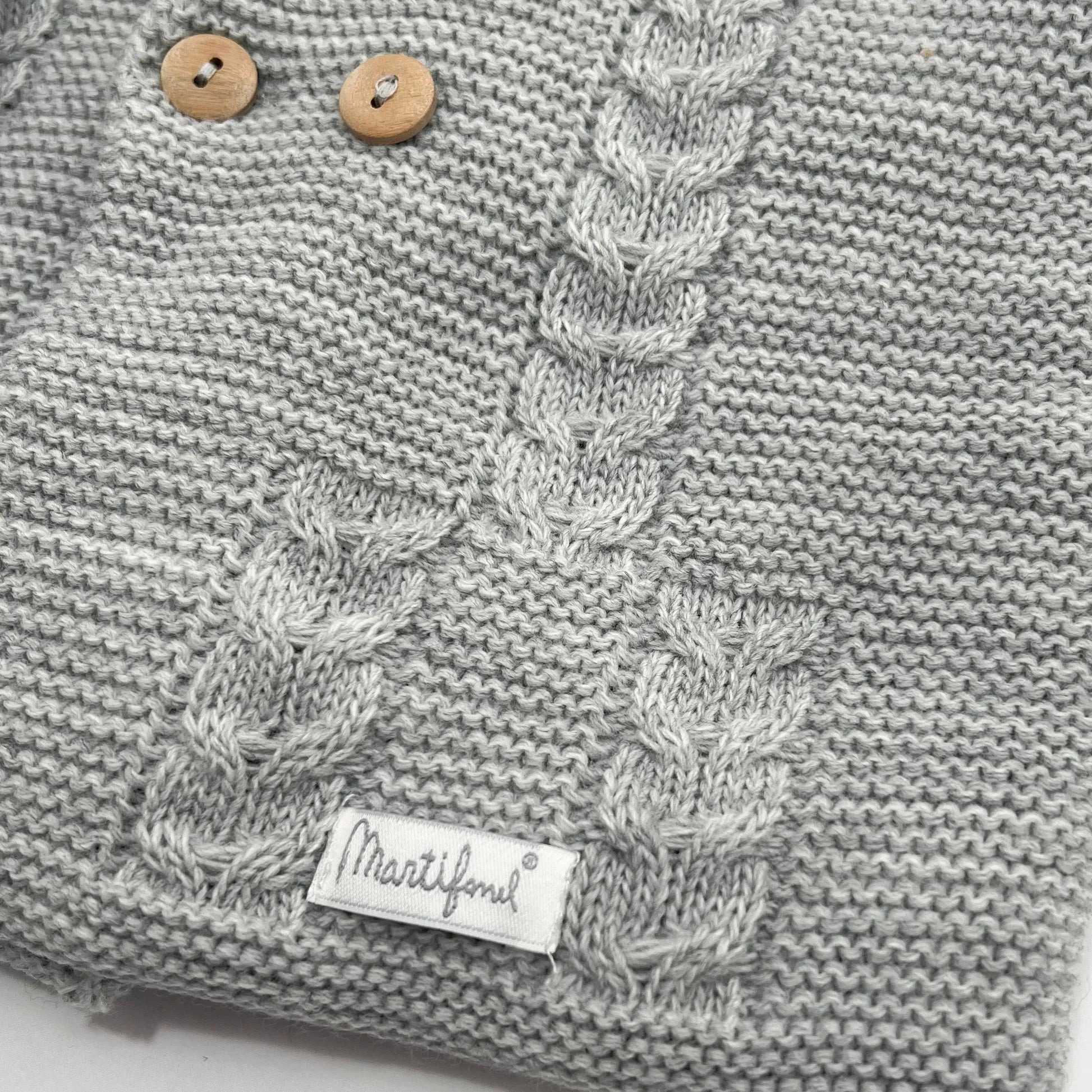 Detalles de chaqueta de punto con capucha y detalles trenzados en la parte delantera gris