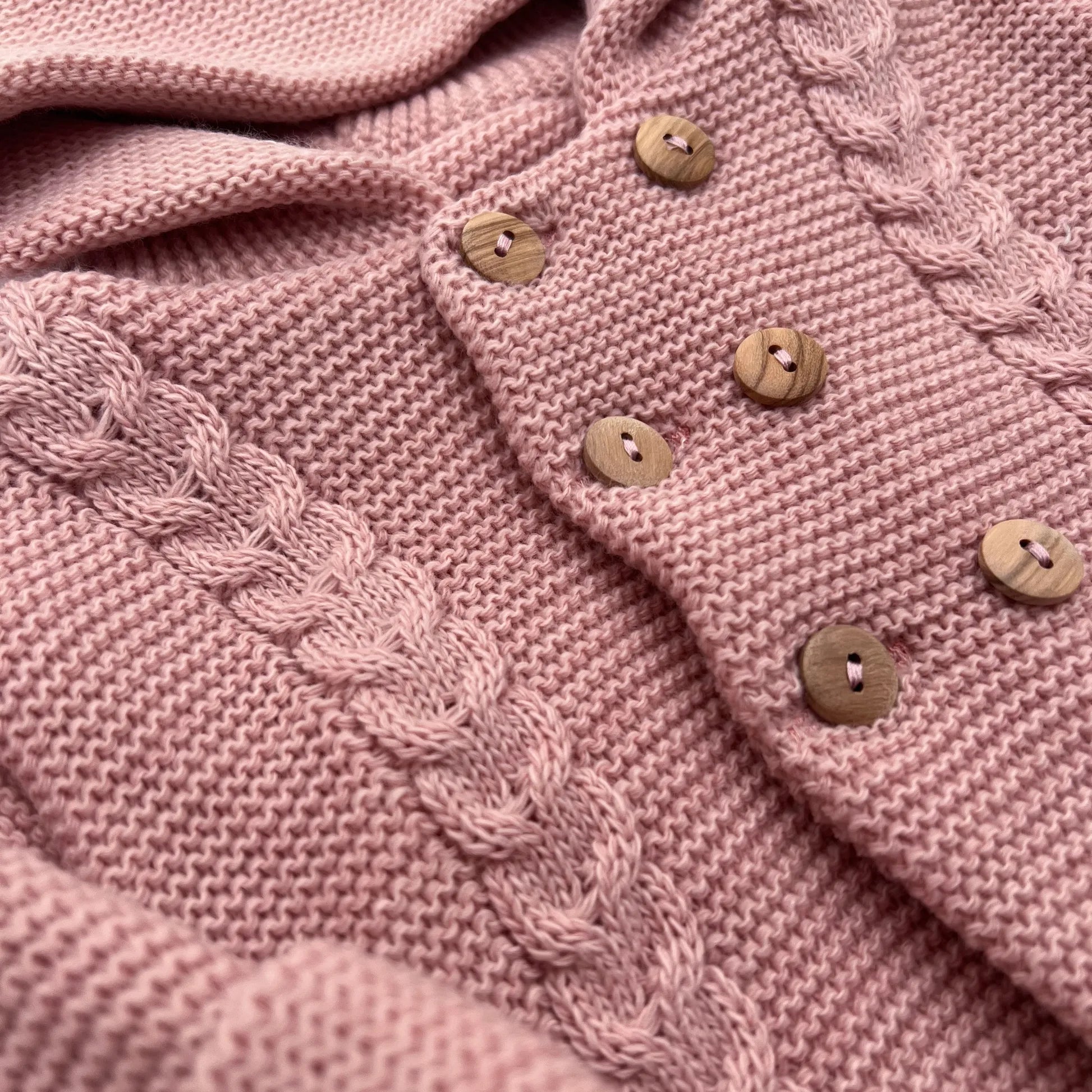 Detalles de chaqueta de punto con capucha y detalles trenzados en la parte delantera rosa