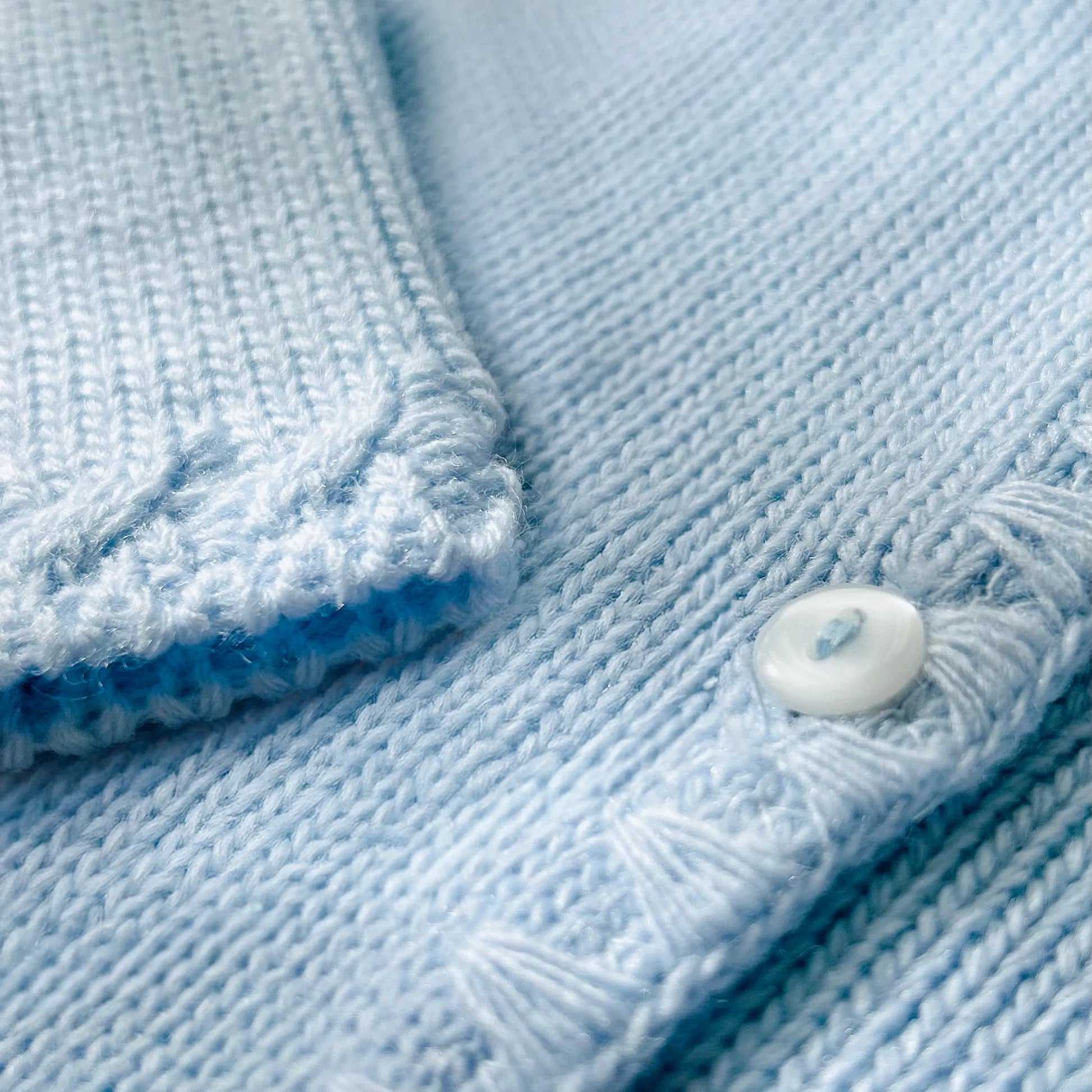 Detalle de chaqueta de punto con detalles trabajados en los bordes azul