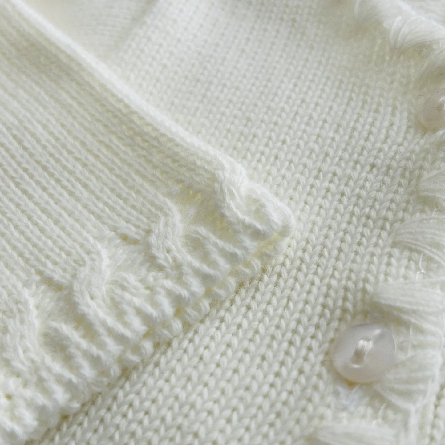Detalle de chaqueta de punto con detalles trabajados en los bordes perla