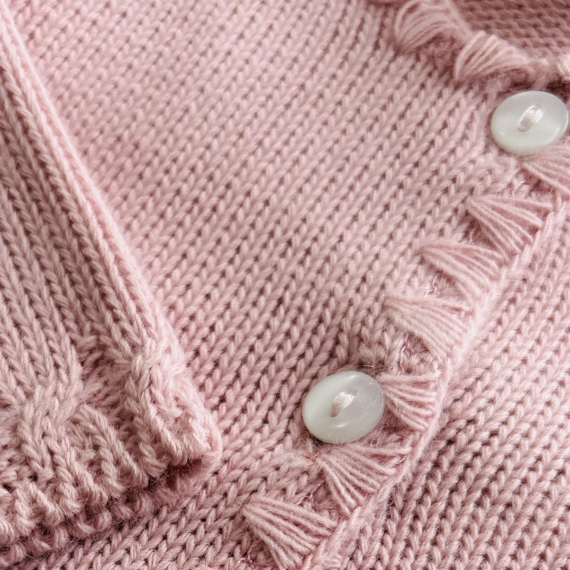 Detalle de chaqueta de punto con detalles trabajados en los bordes rosa