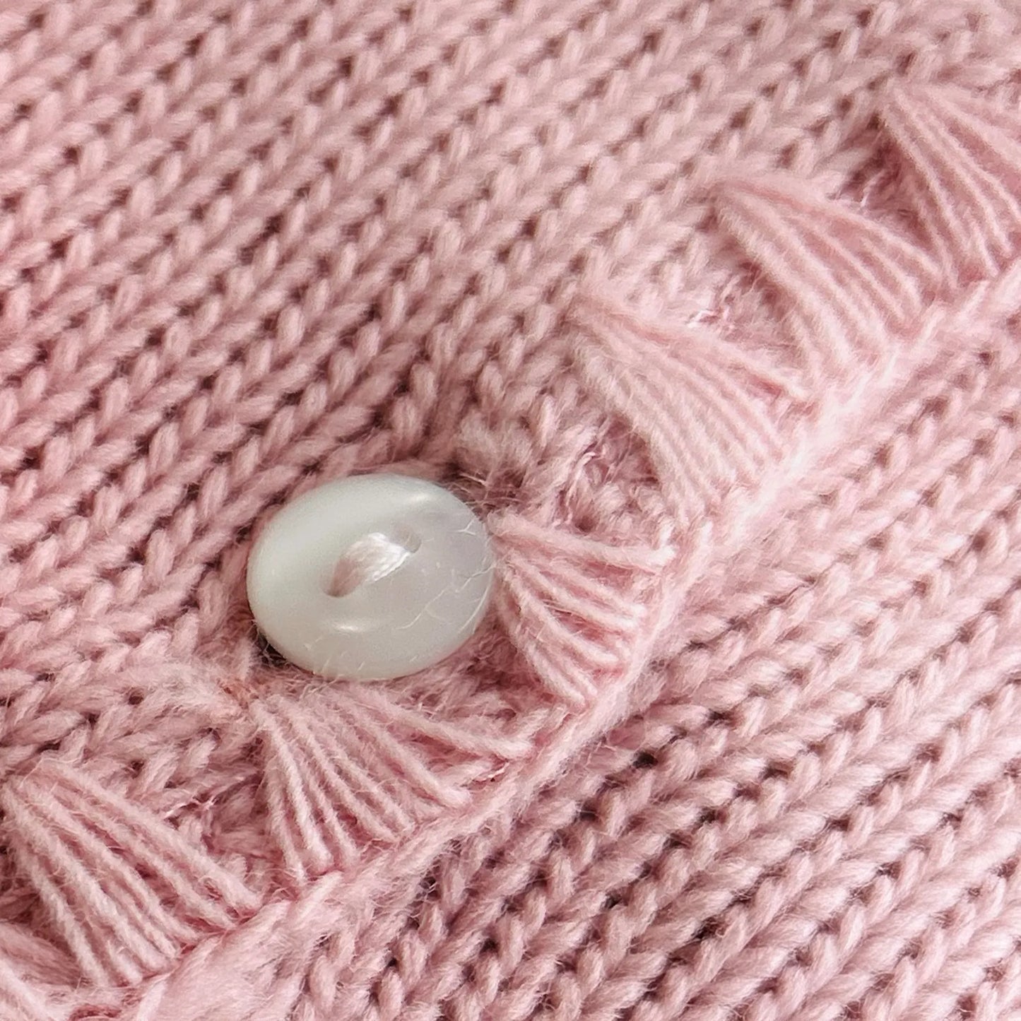 Detalle de chaqueta de punto con detalles trabajados en los bordes rosa