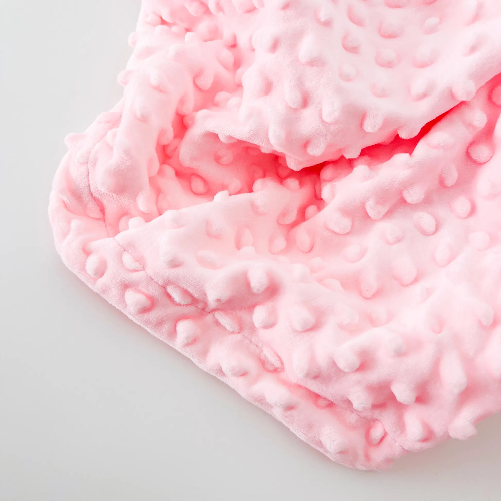 Detalle de conjunto de manta y doudou oveja con detalles en relieve rosa