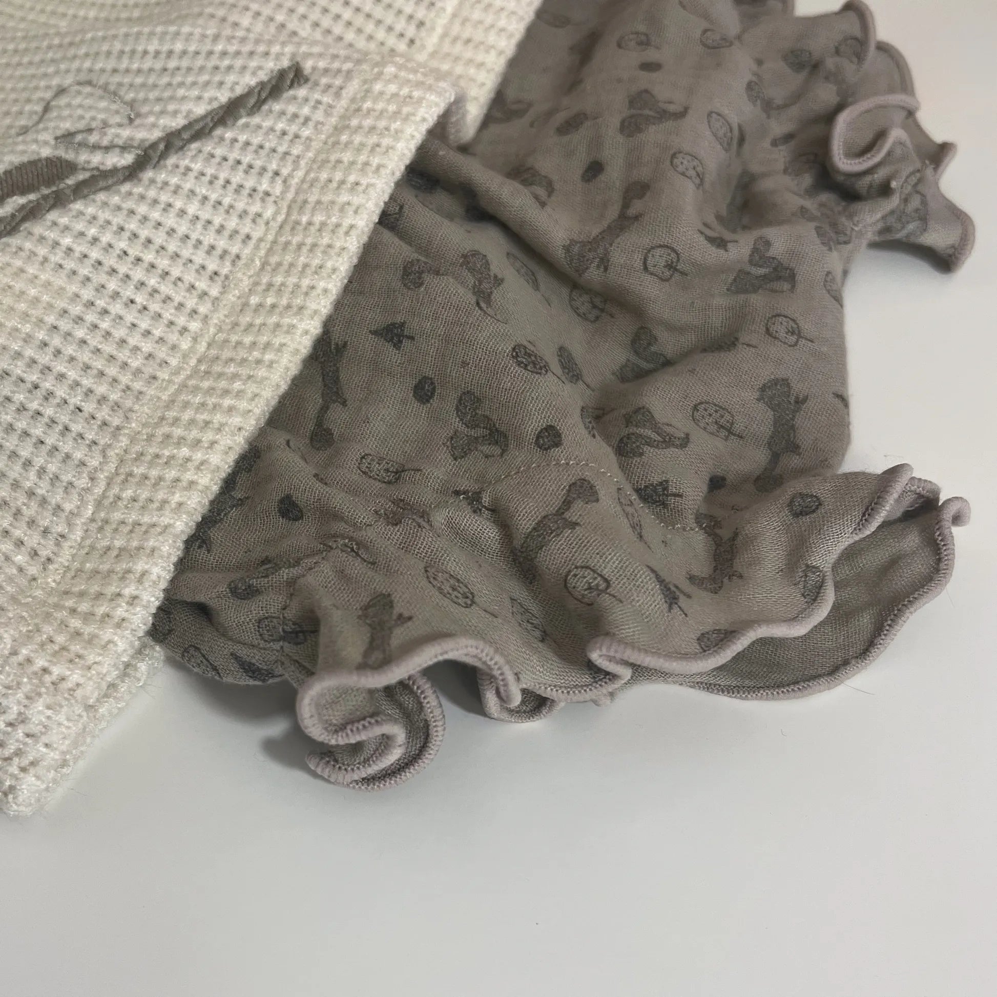 Detalle de conjunto de niña de camiseta color perla con volante en el cuello y cubrepañal gris