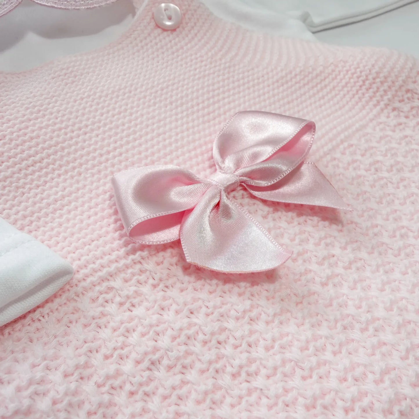 Detalle de conjunto de ni�a de peto con lazo, camiseta y gorro con pomp�n en tricot rosa