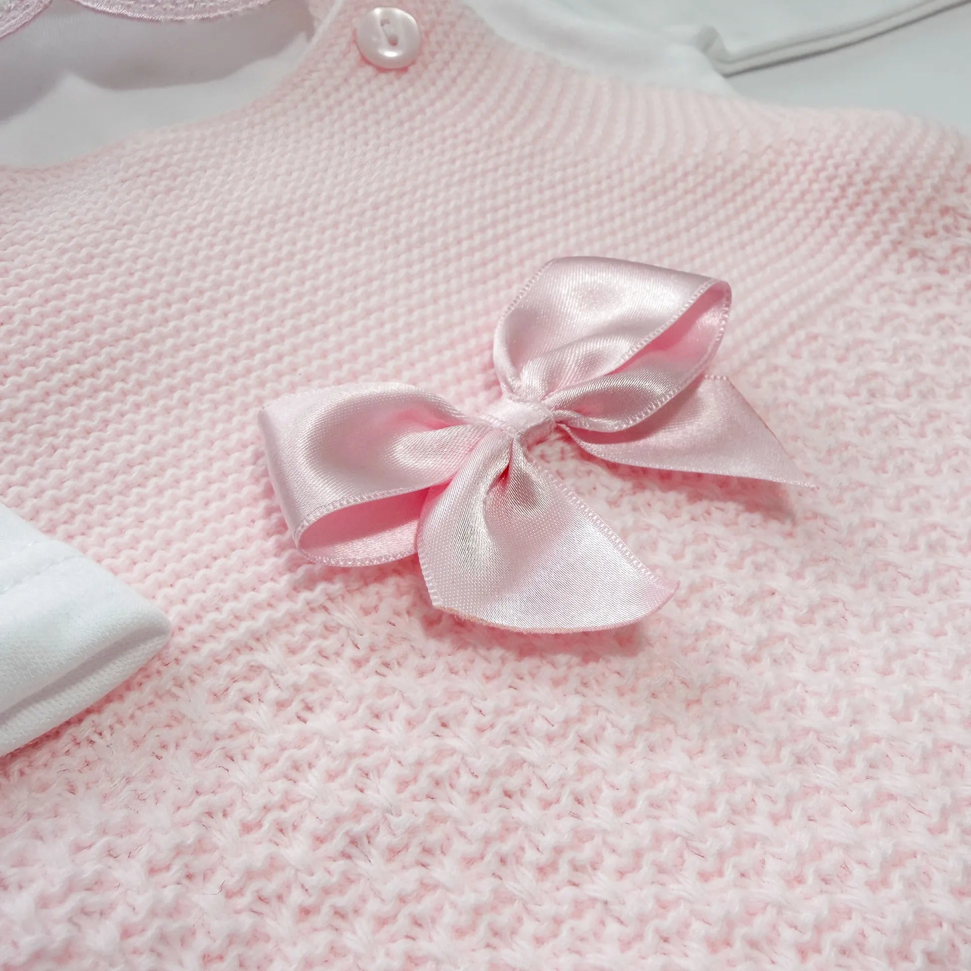 Detalle de conjunto de ni�a de peto con lazo, camiseta y gorro con pomp�n en tricot rosa