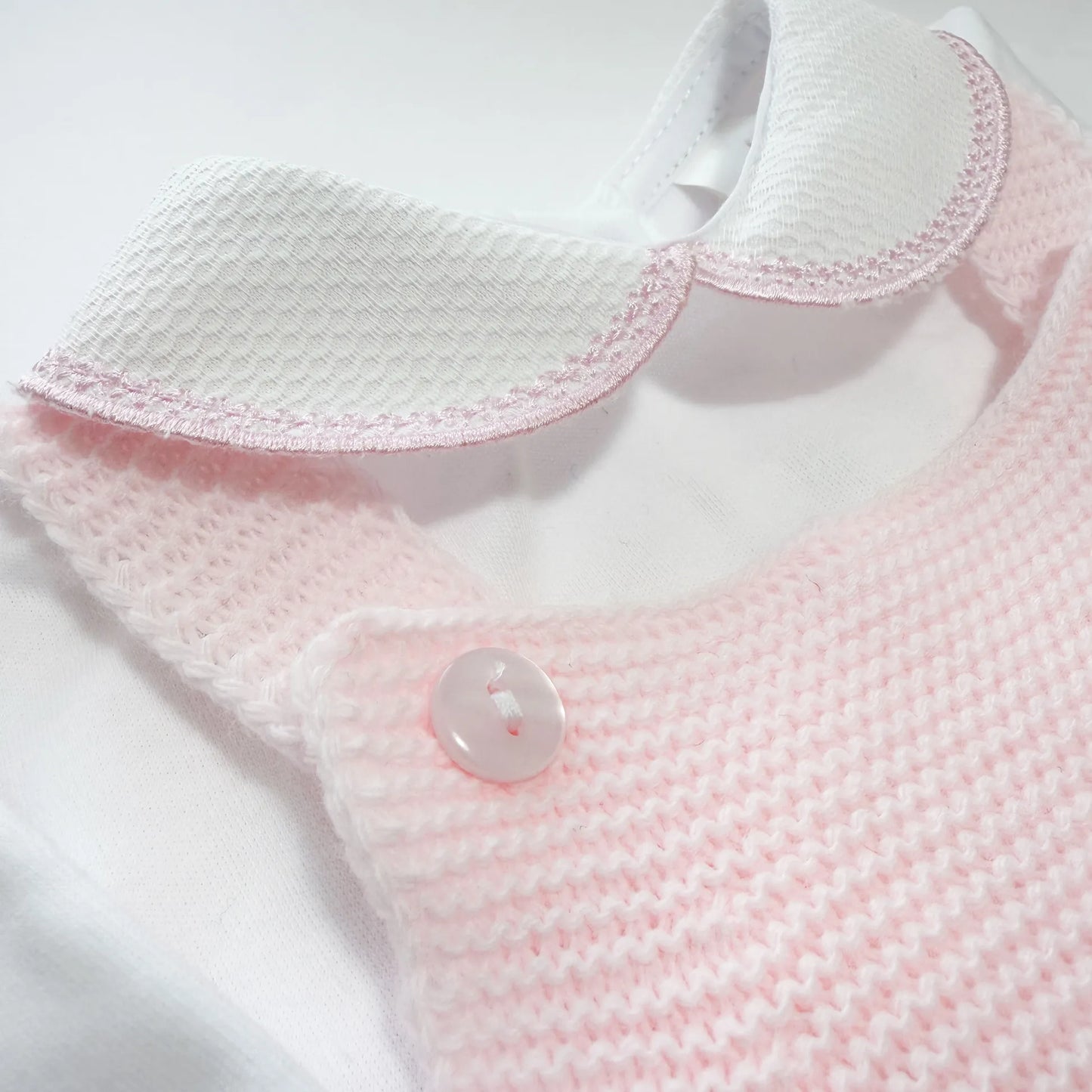Detalle de conjunto de ni�a de peto con lazo, camiseta y gorro con pomp�n en tricot rosa