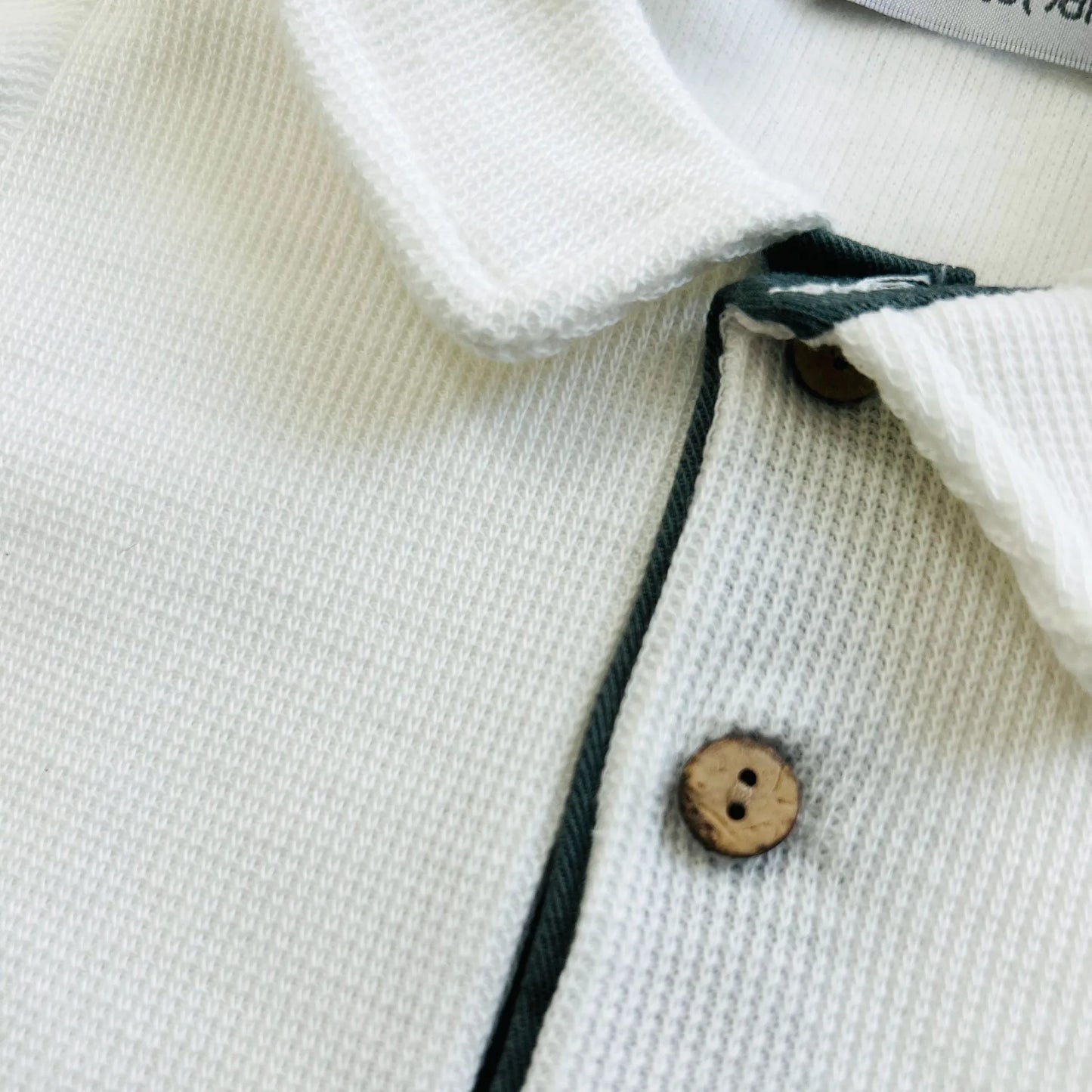 Detalle de conjunto de niño de camiseta color crudo con botones y pantalón corto de tela verde