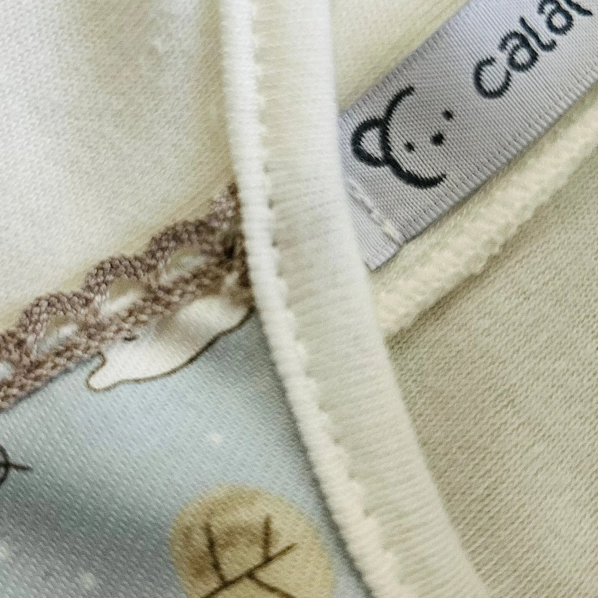 Detalle de conjunto de niño de camiseta blanca con faja decorativa y cubrepañal gris