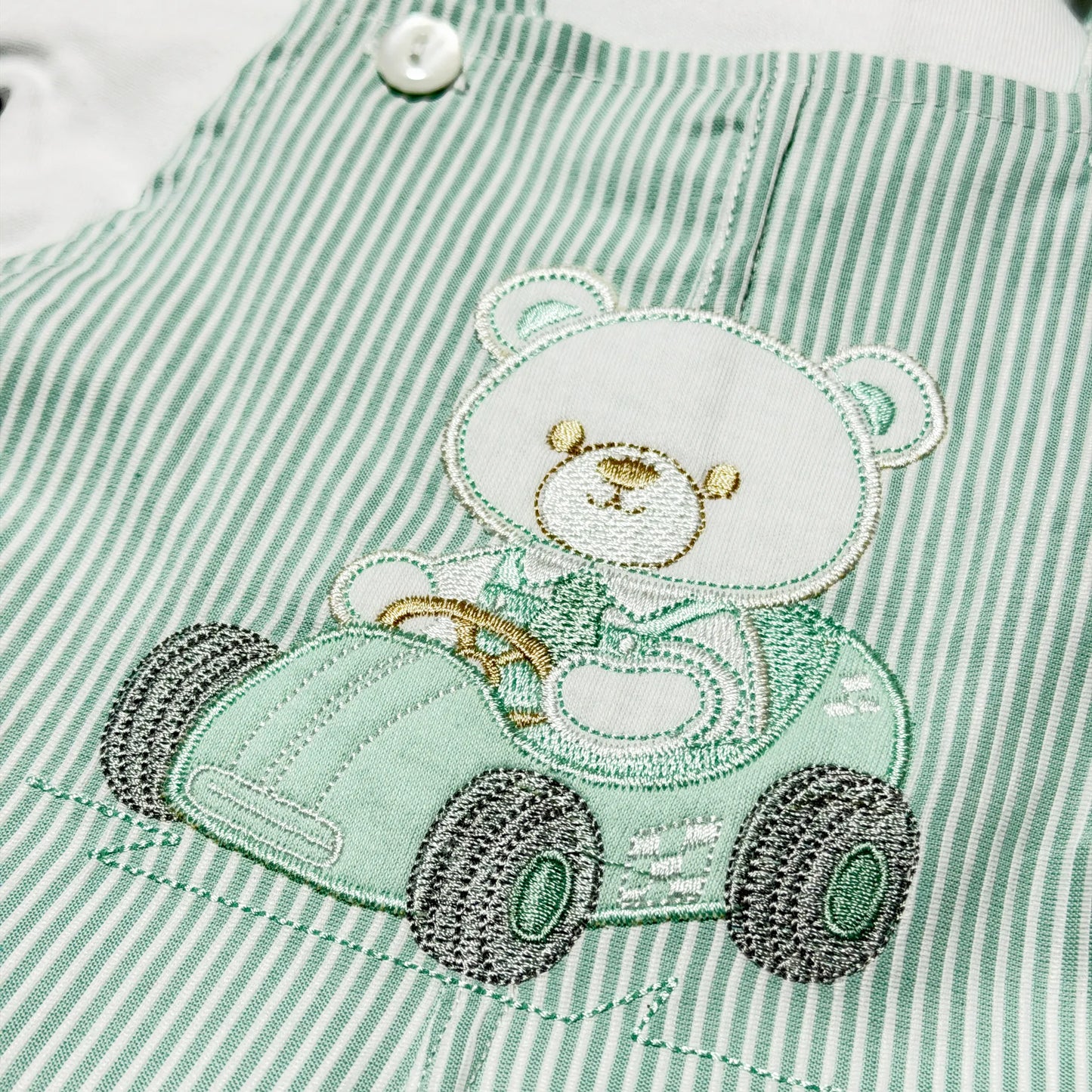 Detalle de conjunto de niño de peto a rayas con motivo bordado de osito verde