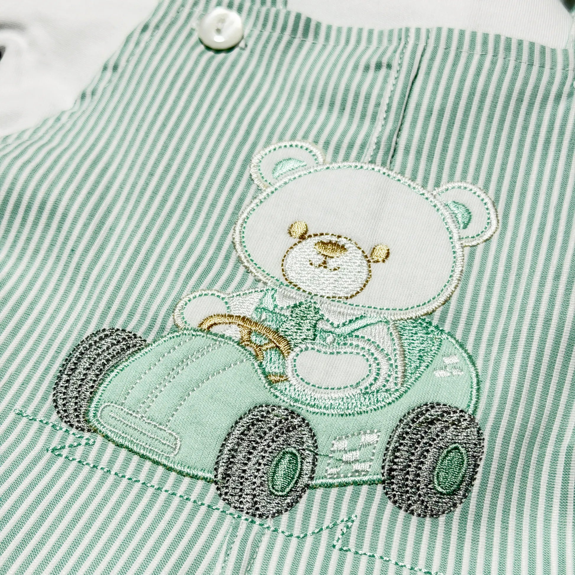 Detalle de conjunto de niño de peto a rayas con motivo bordado de osito verde