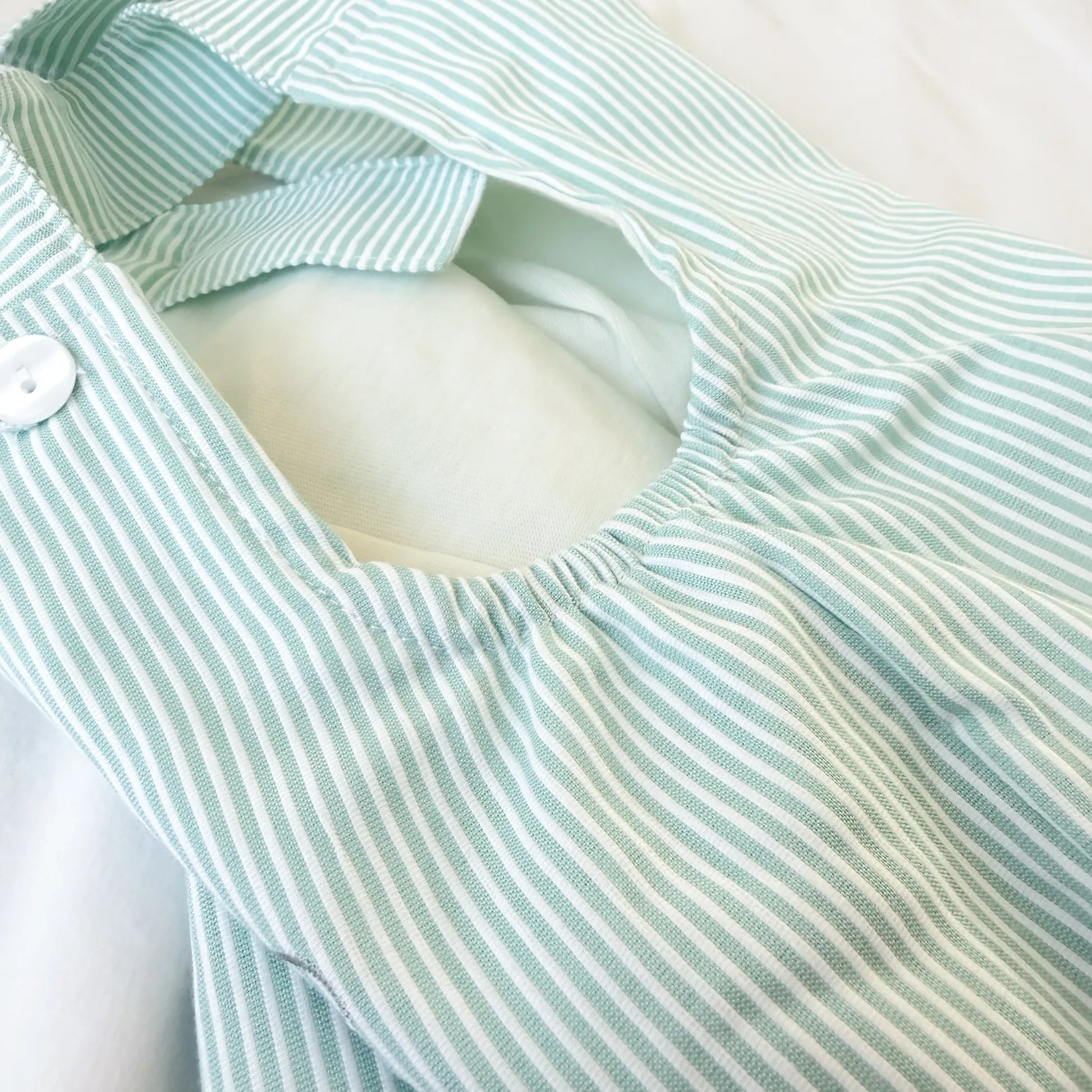 Detalle de conjunto de niño de peto a rayas con motivo bordado verde