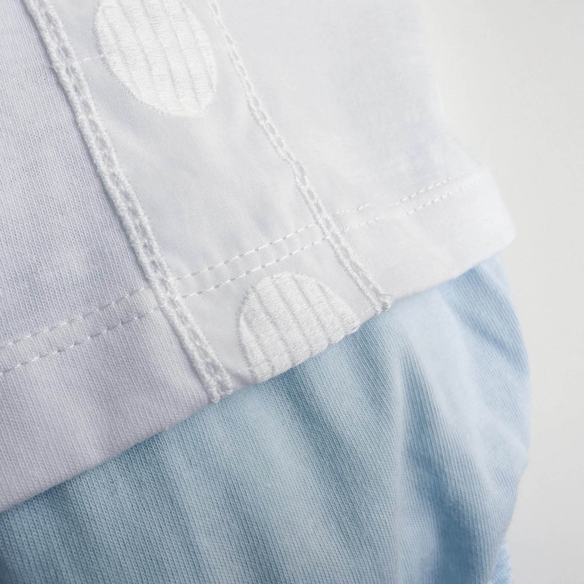 Detalle de conjunto de niño de camiseta con tira decorativa bordada y cubrepañal azul