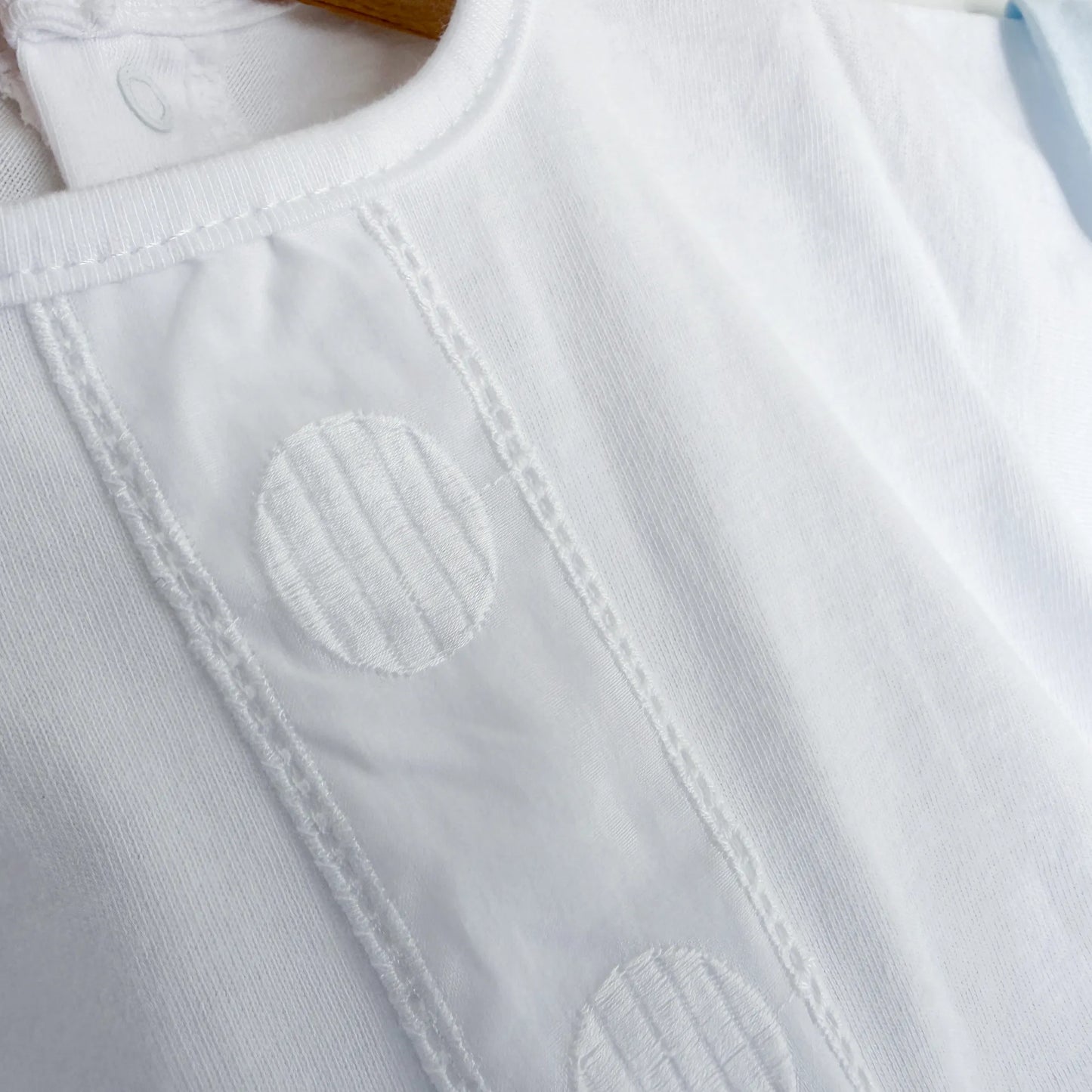 Detalle de conjunto de niño de camiseta con tira decorativa bordada y cubrepañal azul