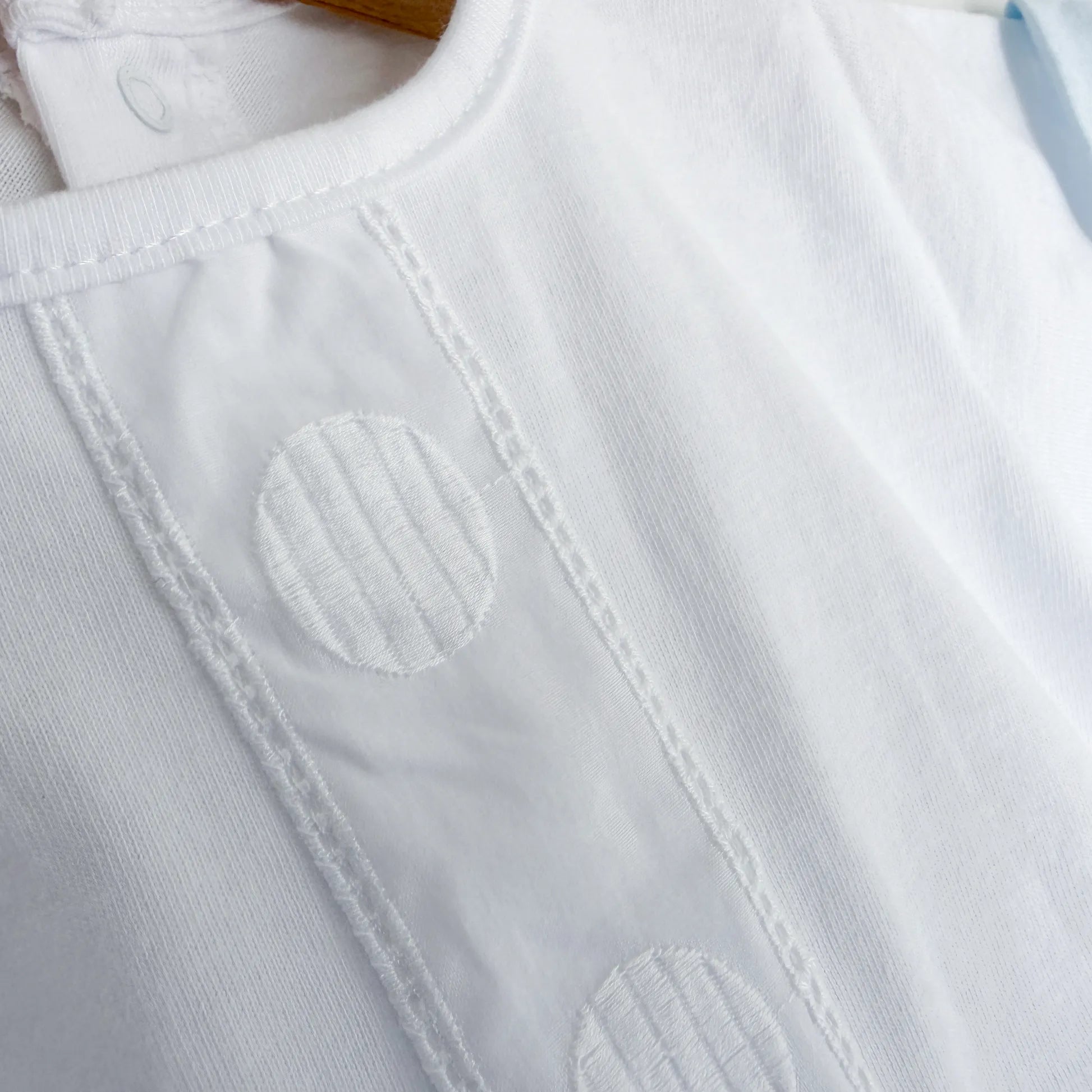 Detalle de conjunto de niño de camiseta con tira decorativa bordada y cubrepañal azul