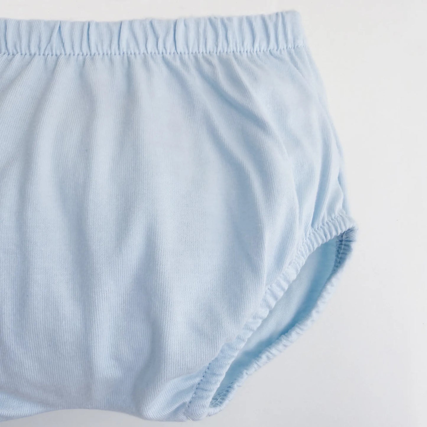 Detalle de conjunto de niño de camiseta con tira decorativa bordada y cubrepañal azul