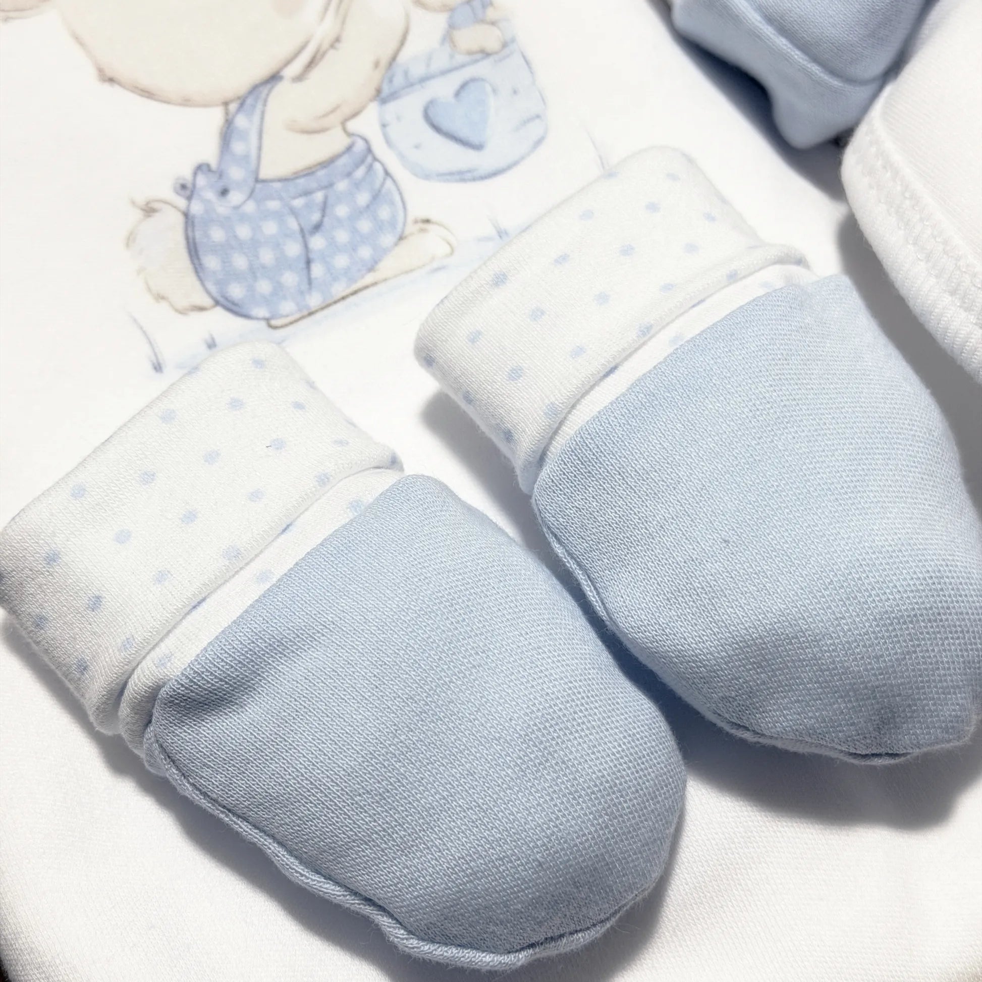 Detalle de conjunto de primera puesta con motivo de conejito en la cesta azul