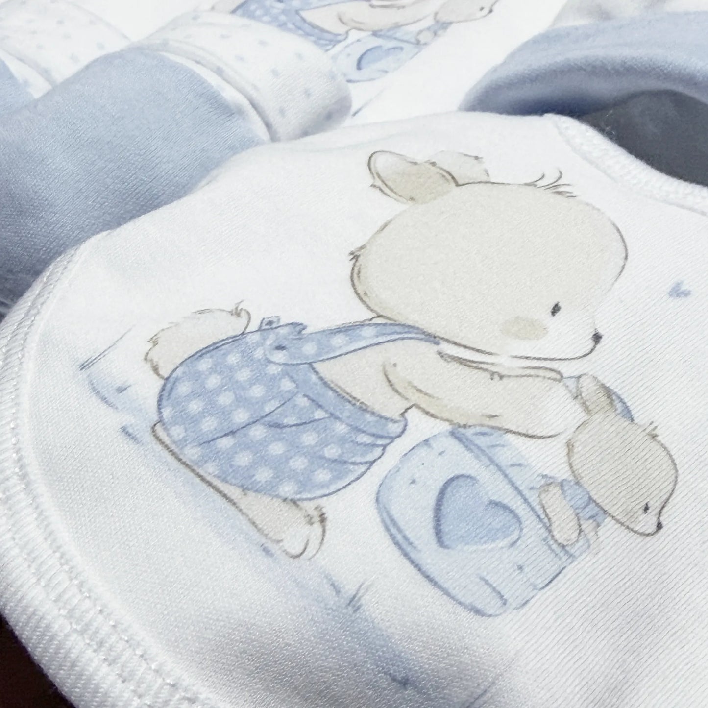 Detalle de conjunto de primera puesta con motivo de conejito en la cesta azul