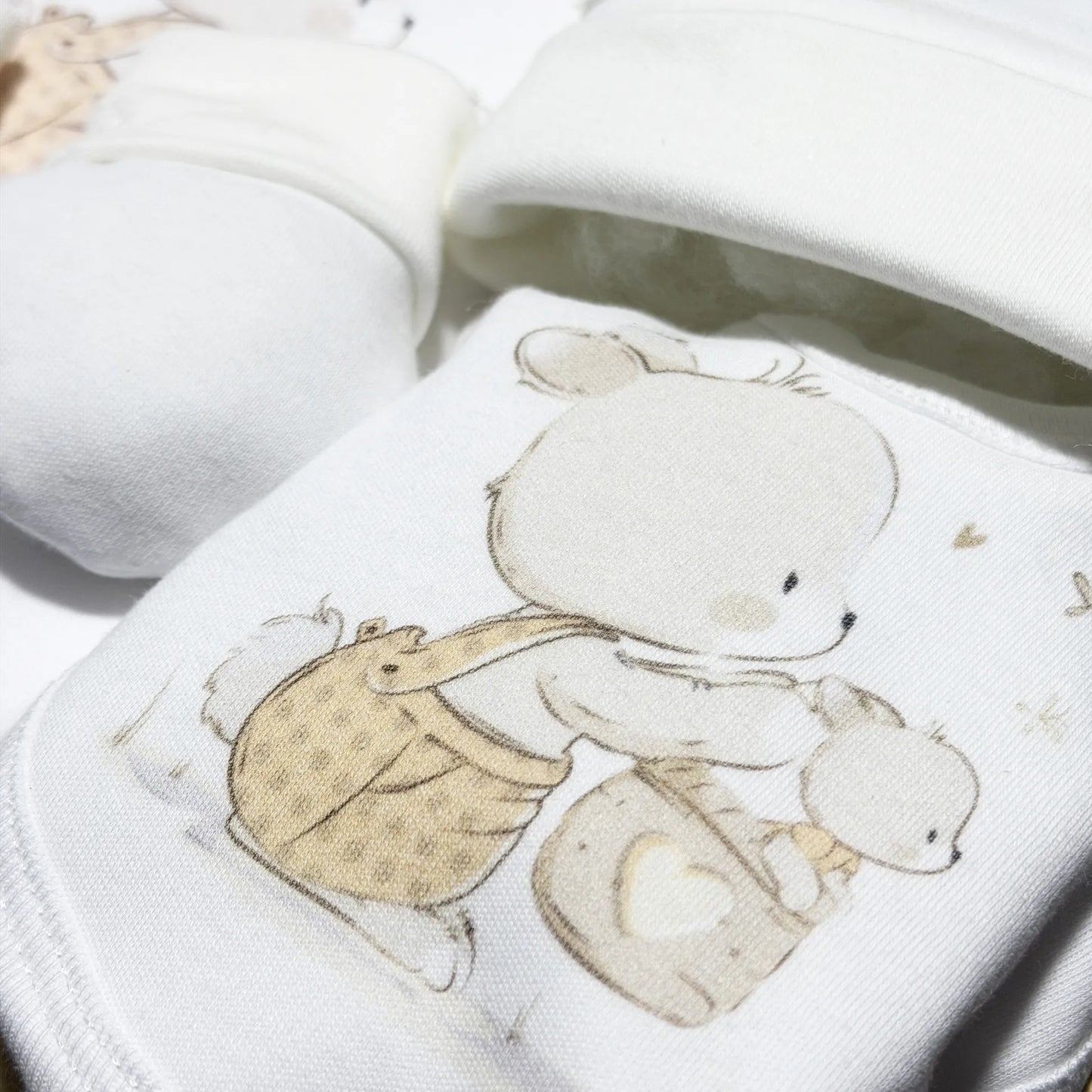 Detalle de conjunto de primera puesta con motivo de conejito en la cesta beige