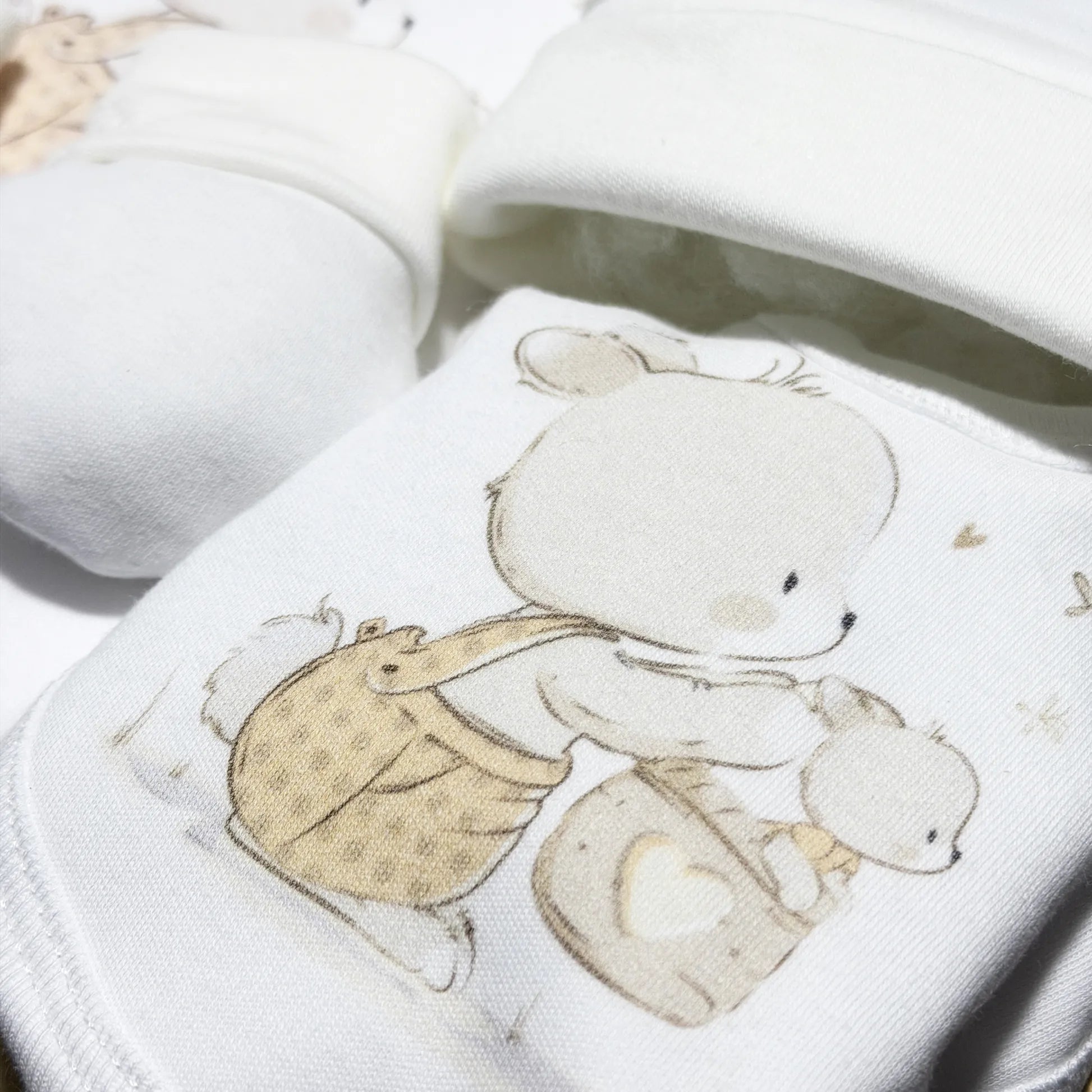 Detalle de conjunto de primera puesta con motivo de conejito en la cesta beige