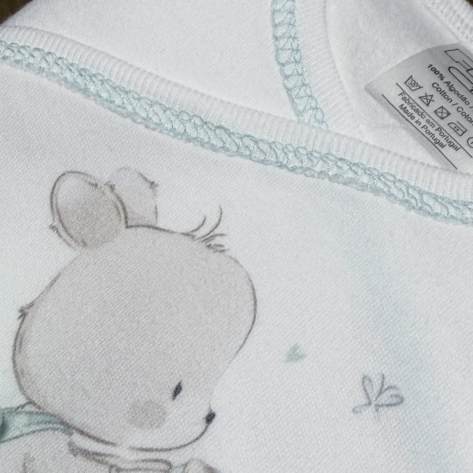 Detalle de conjunto de primera puesta con motivo de conejito en la cesta verde
