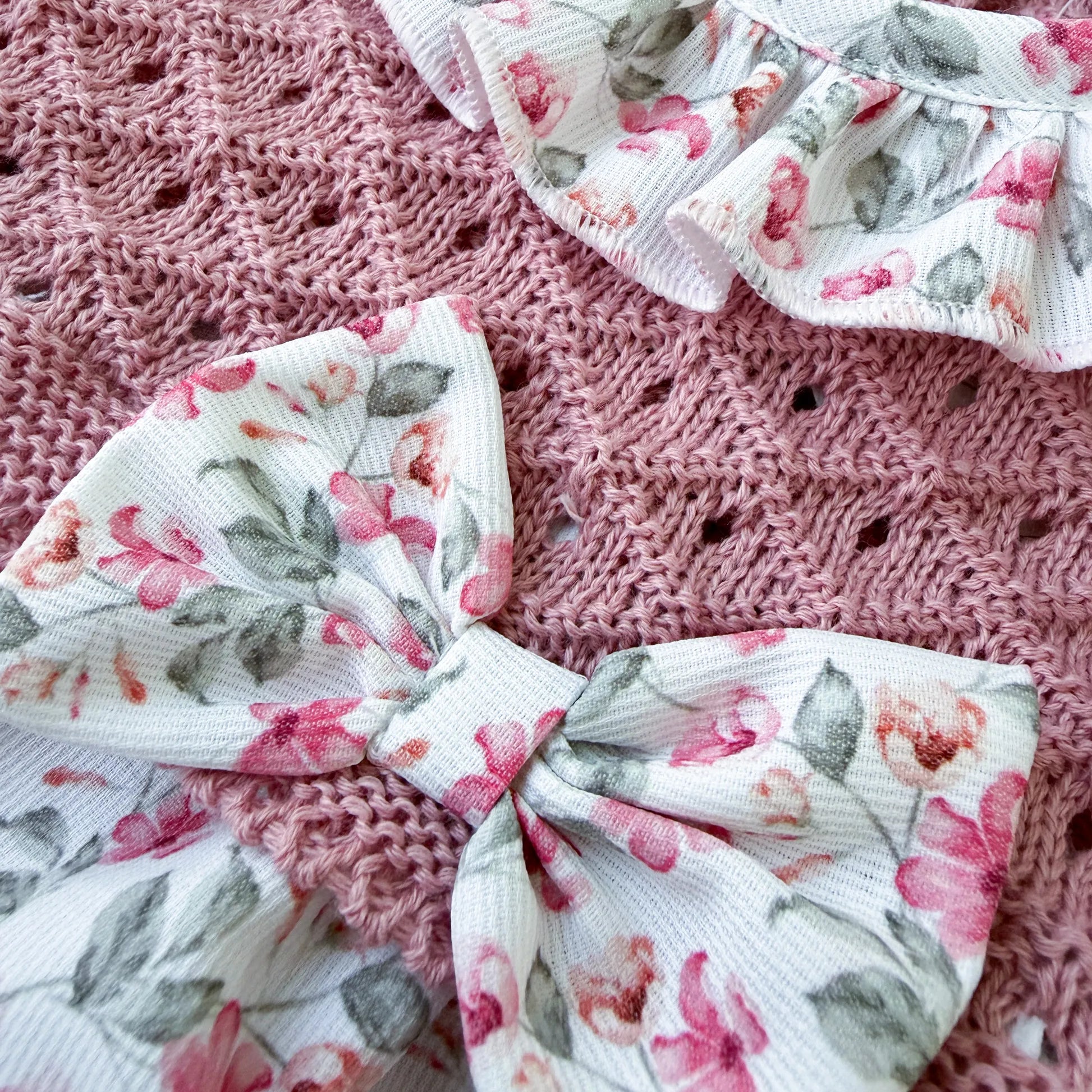 Detalle de ranita de niña de estampado floral con volante en el cuello y lazo en la frente