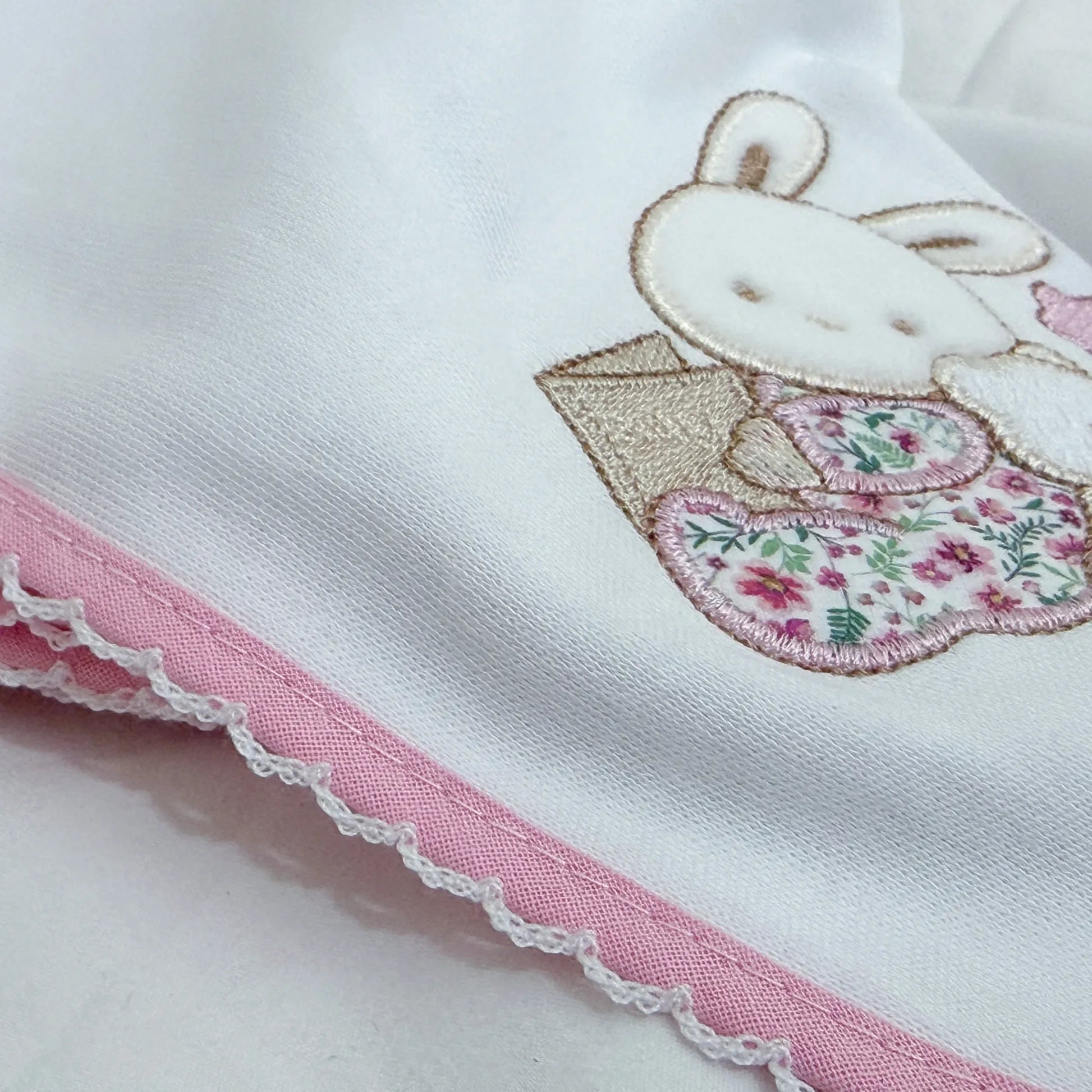 Detalle de paño para eructar con motivo de conejito y osito con libro rosa