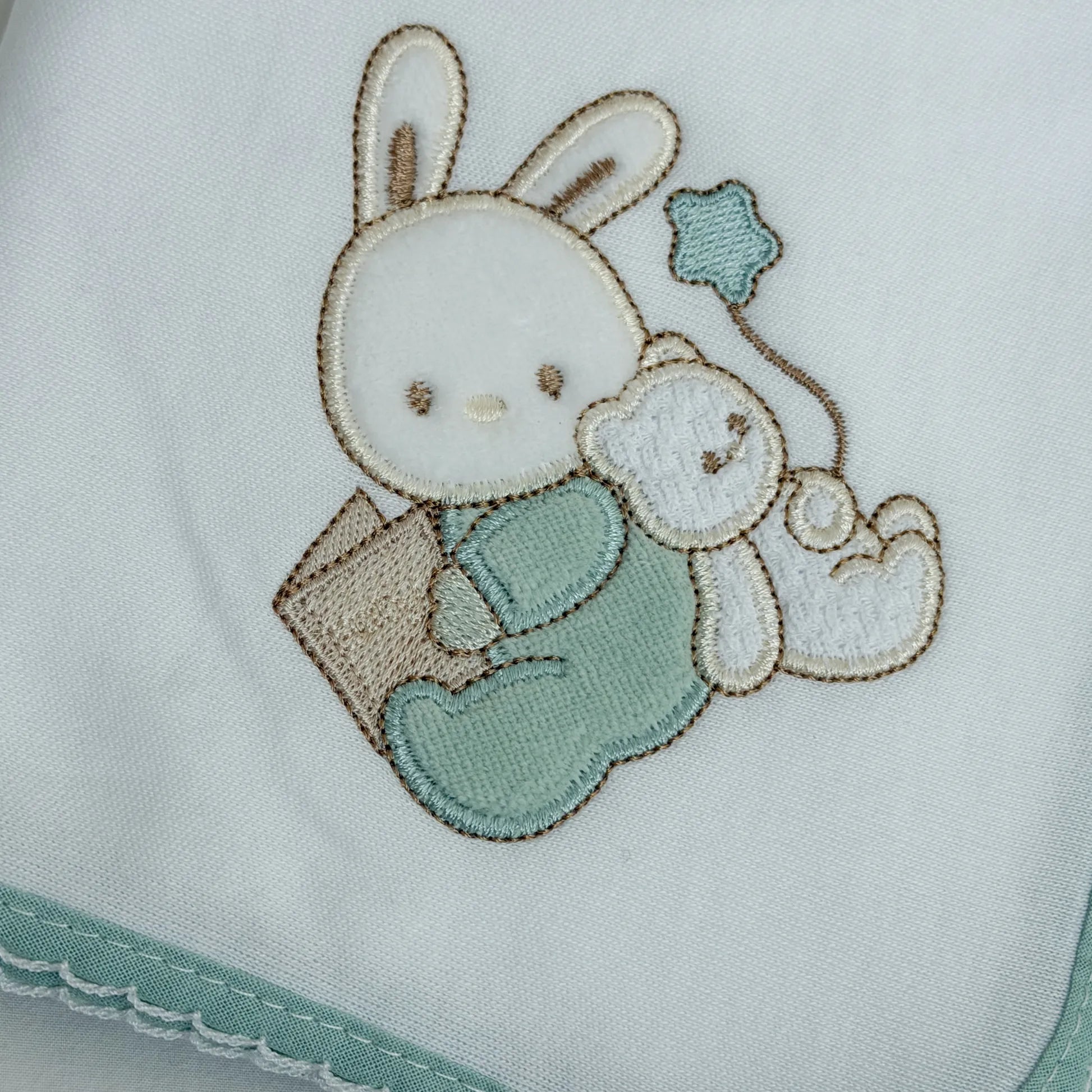 Detalle de paño para eructar con motivo de conejito y osito con libro verde