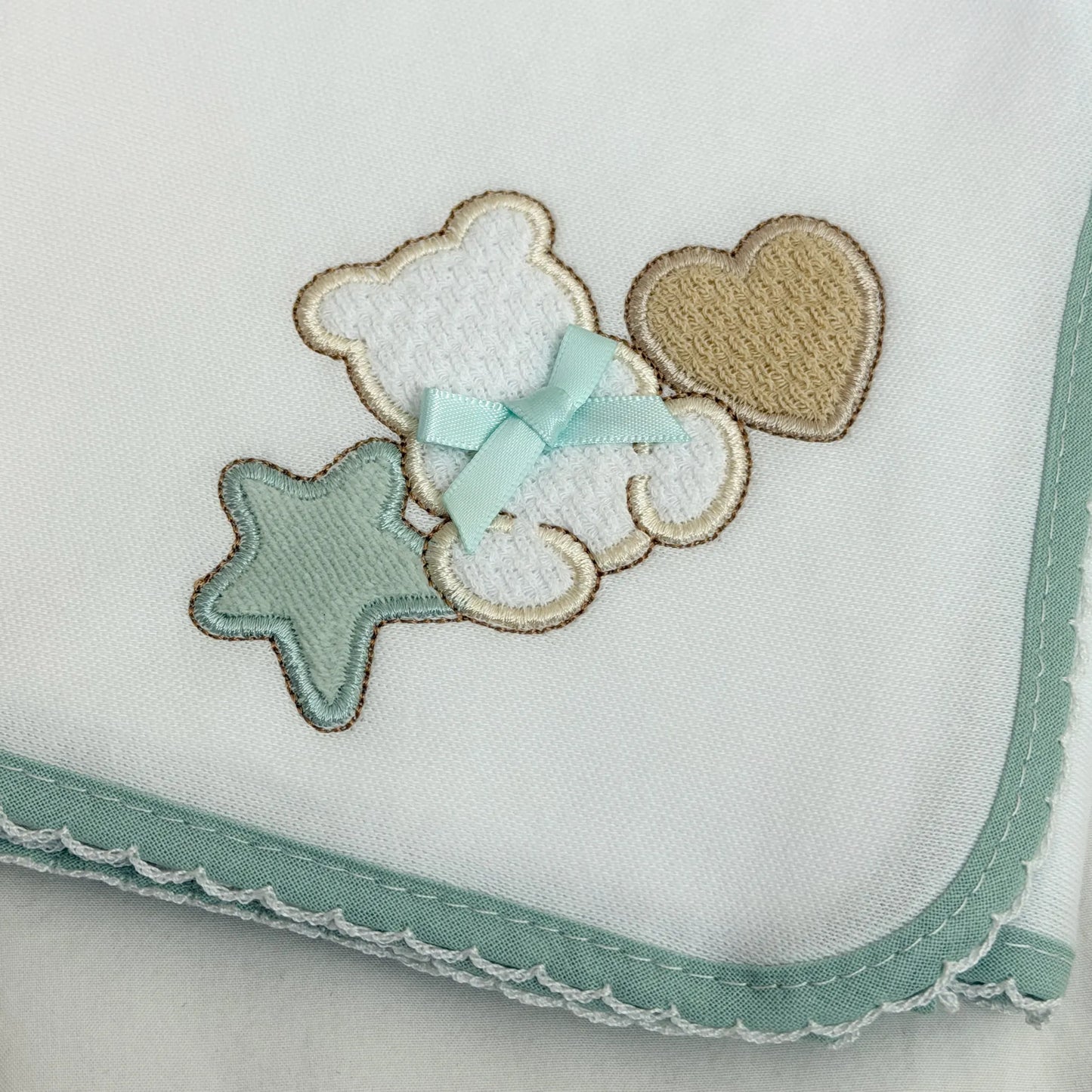 Detalle de paño para eructar con motivo de osito entre estrella y corazón verde