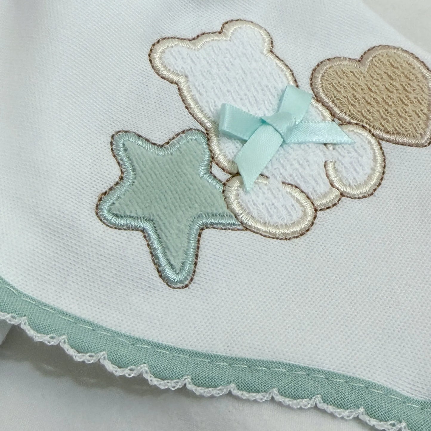 Detalle de paño para eructar con motivo de osito entre estrella y corazón verde