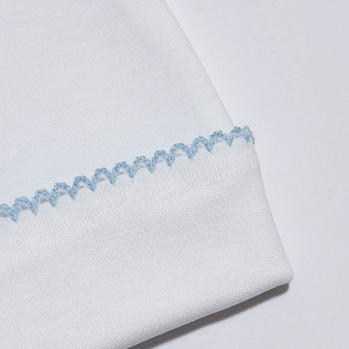 Detalle de gorro blanco con puntilla de color en el doblez azul